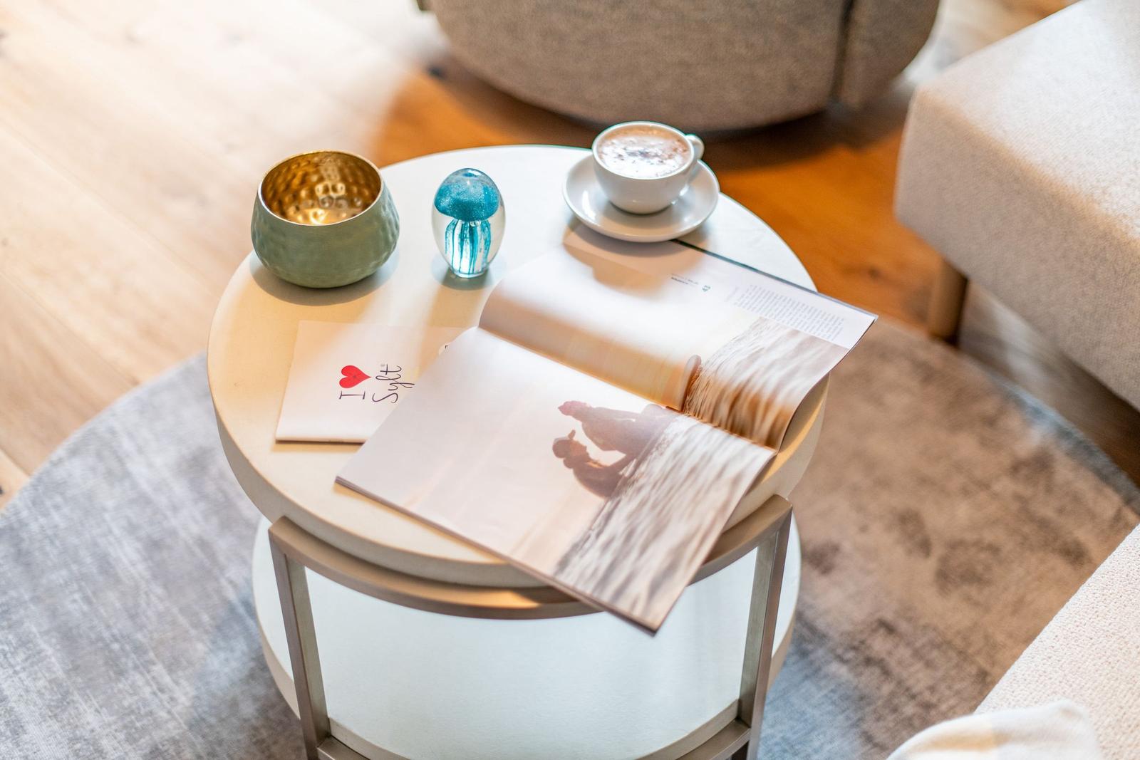 Runder Tisch mit Kaffee, Buch und Dekorationsgegenständen.