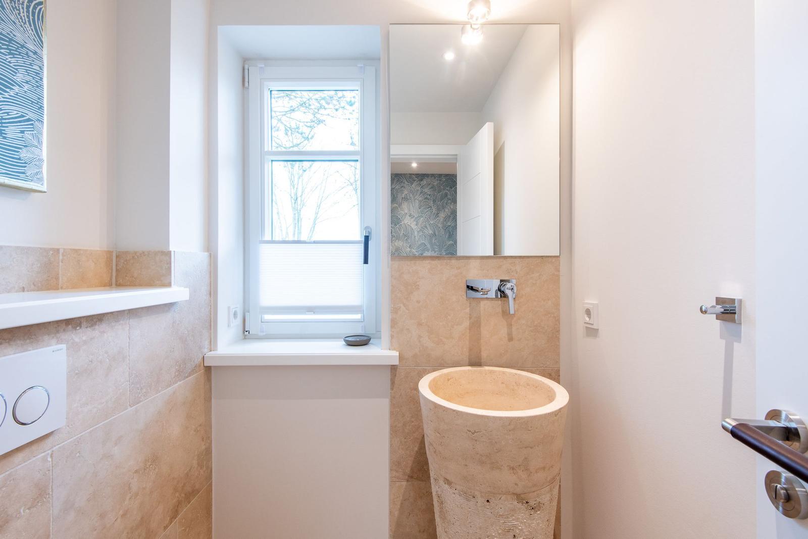 Badezimmer mit Steinwaschbecken, Fenster und Spiegel