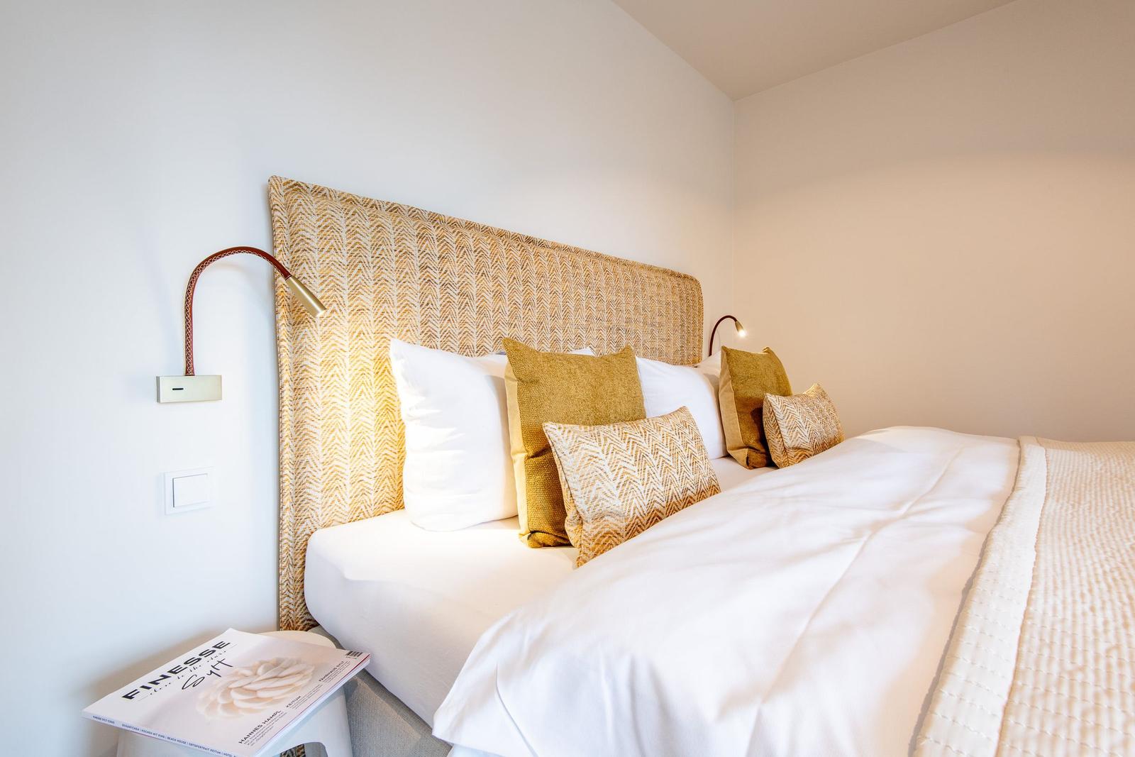 Schlafzimmer mit Bett, Kissen und Wandlampen.