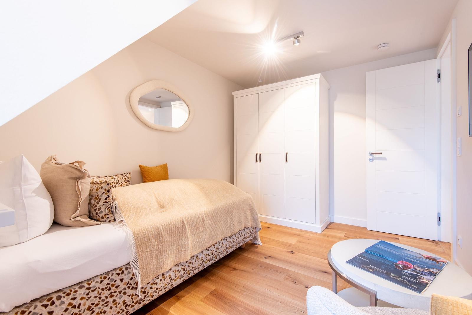 Schlafzimmer mit Bett, Kleiderschrank und runden Tisch.