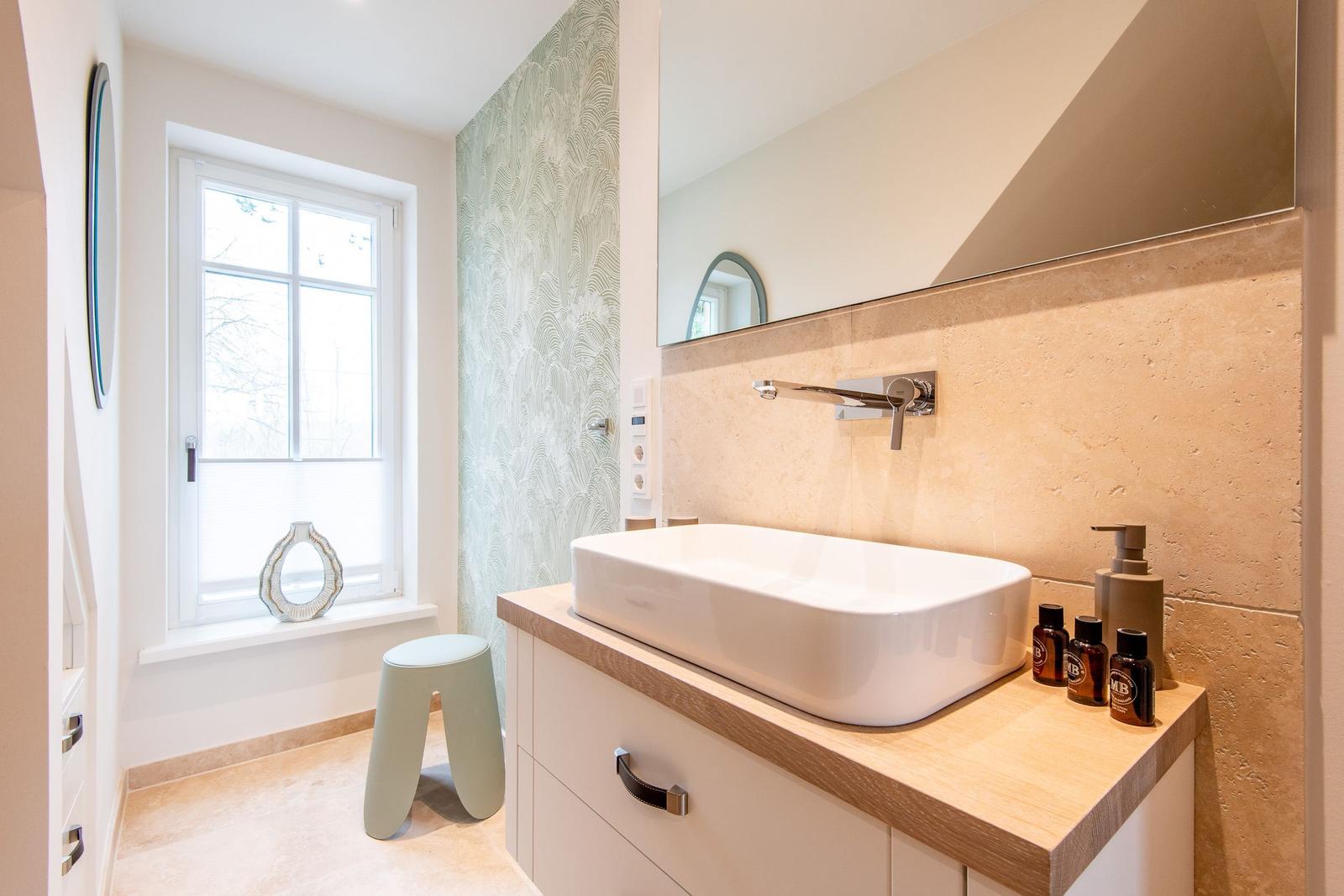 Badezimmer mit Waschbecken, Spiegel und Fenster. Holzoberfläche und Wandverkleidung.