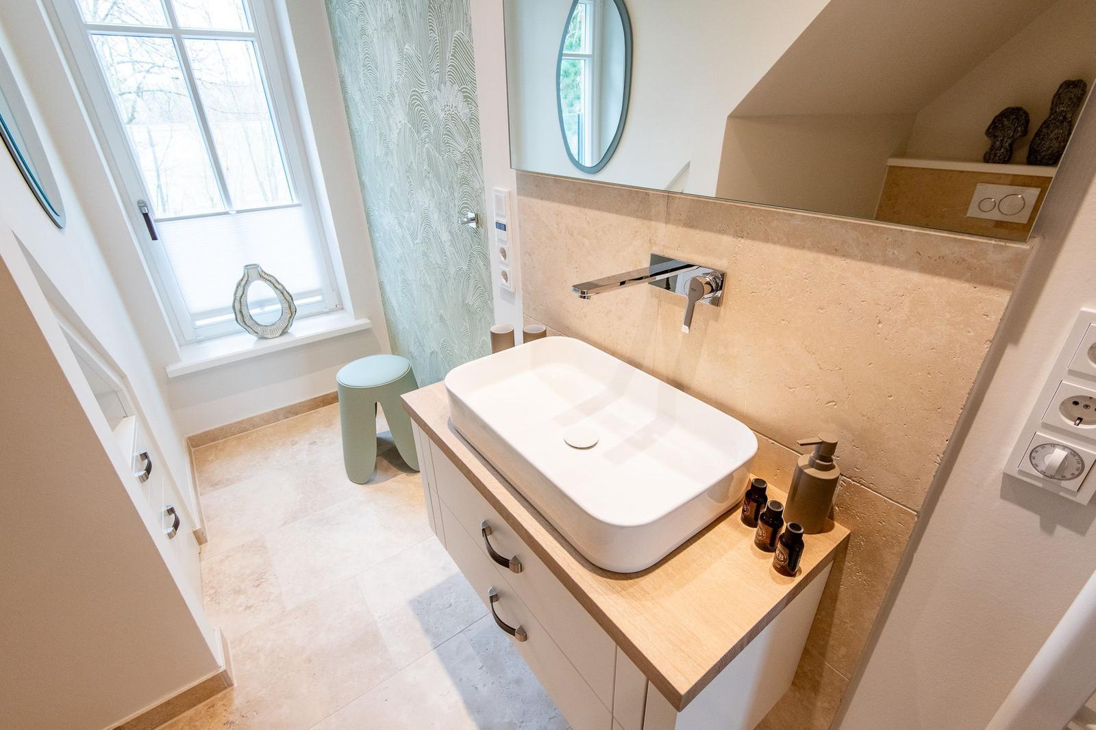 Bad mit Waschtisch, Spiegel und Fenster. Holzoberfläche und Wandfliesen.