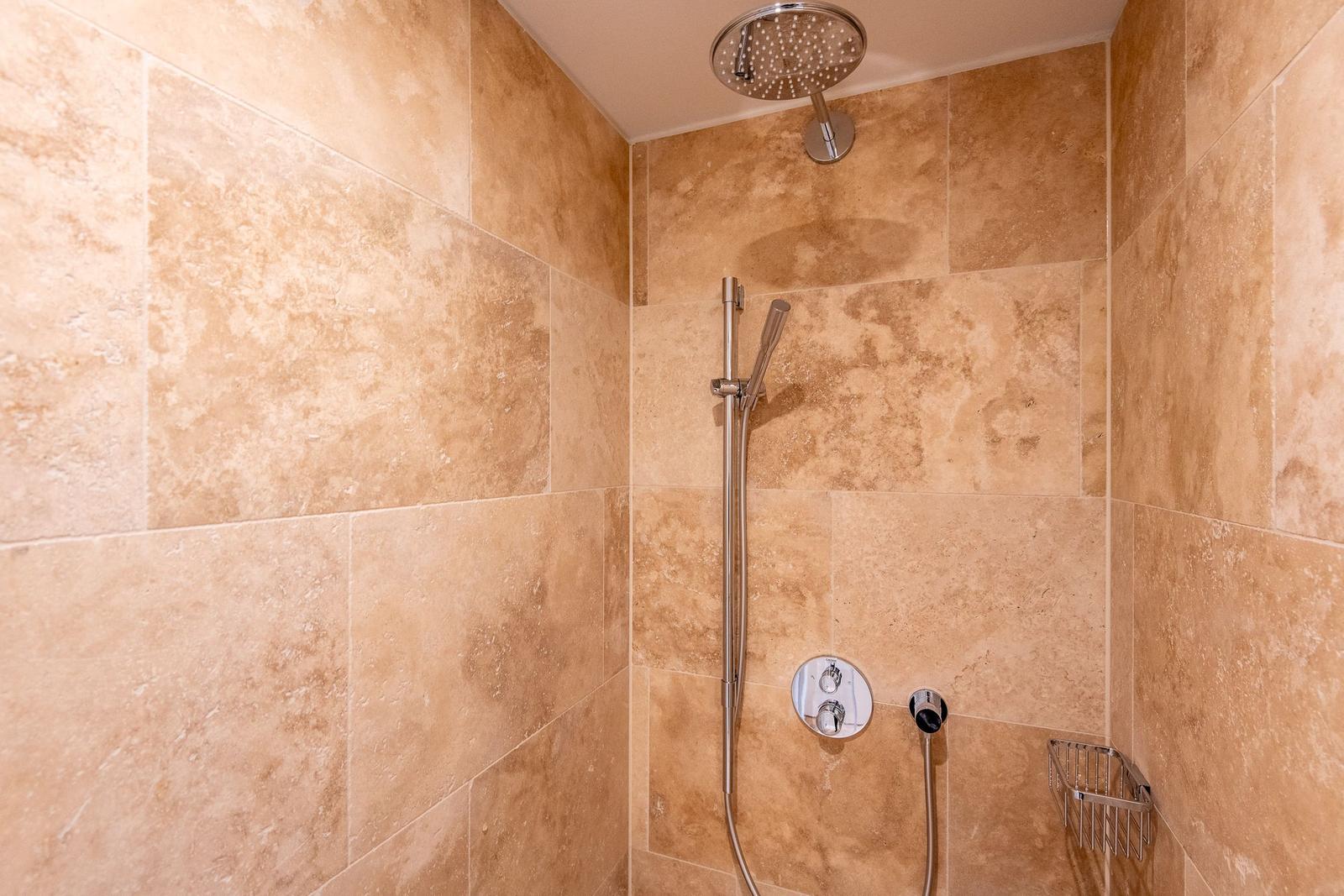 Dusche mit Duschbrause und Handbrause an Wand