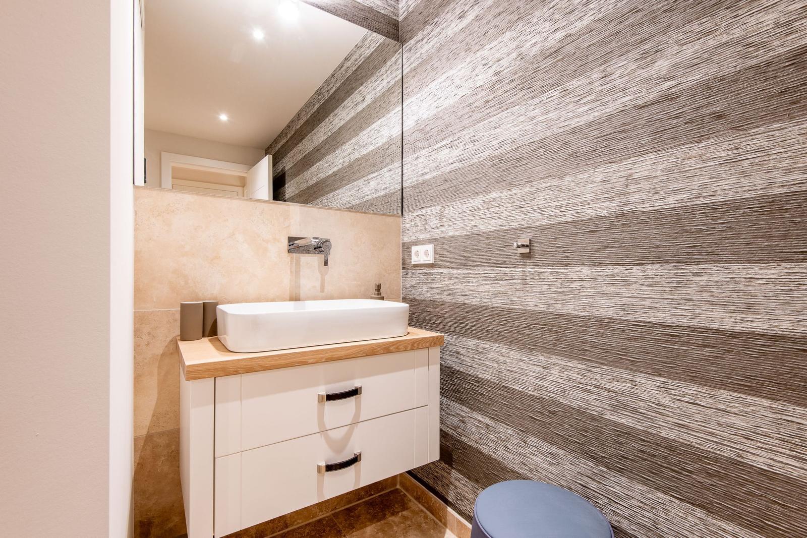 Badezimmer mit Waschbecken, Spiegel und Holzwand