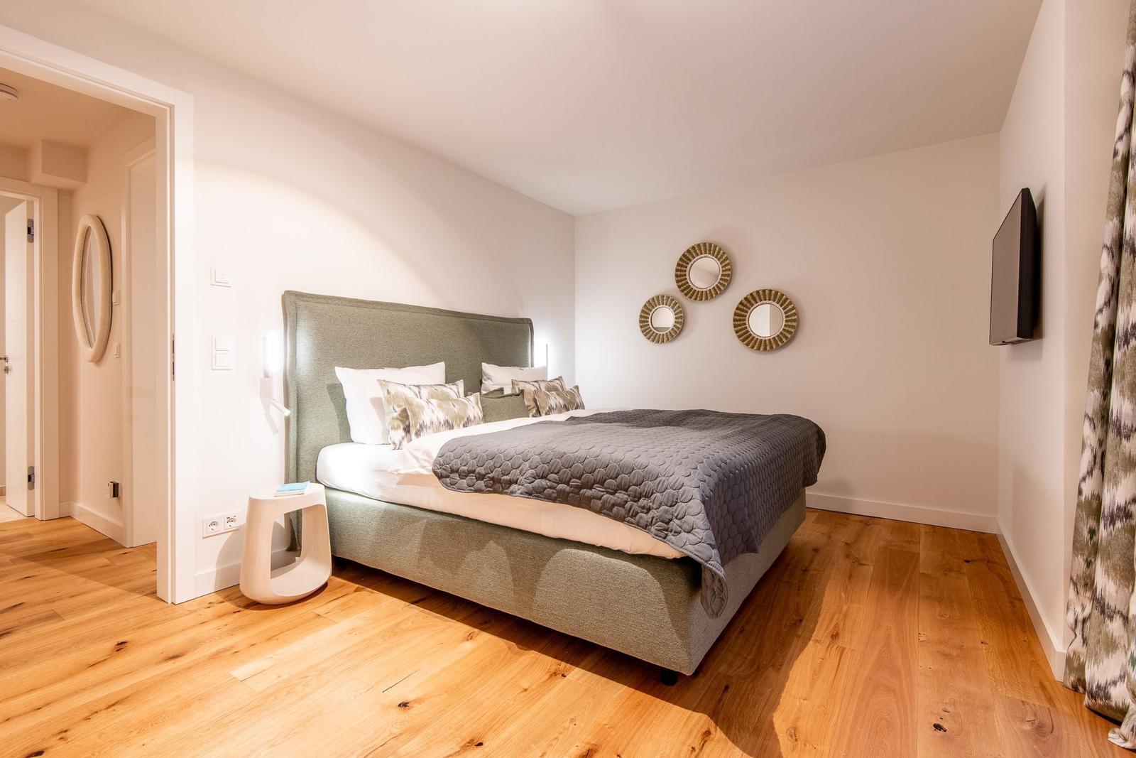 Schlafzimmer mit Bett, Wandspiegeln und Holzboden.