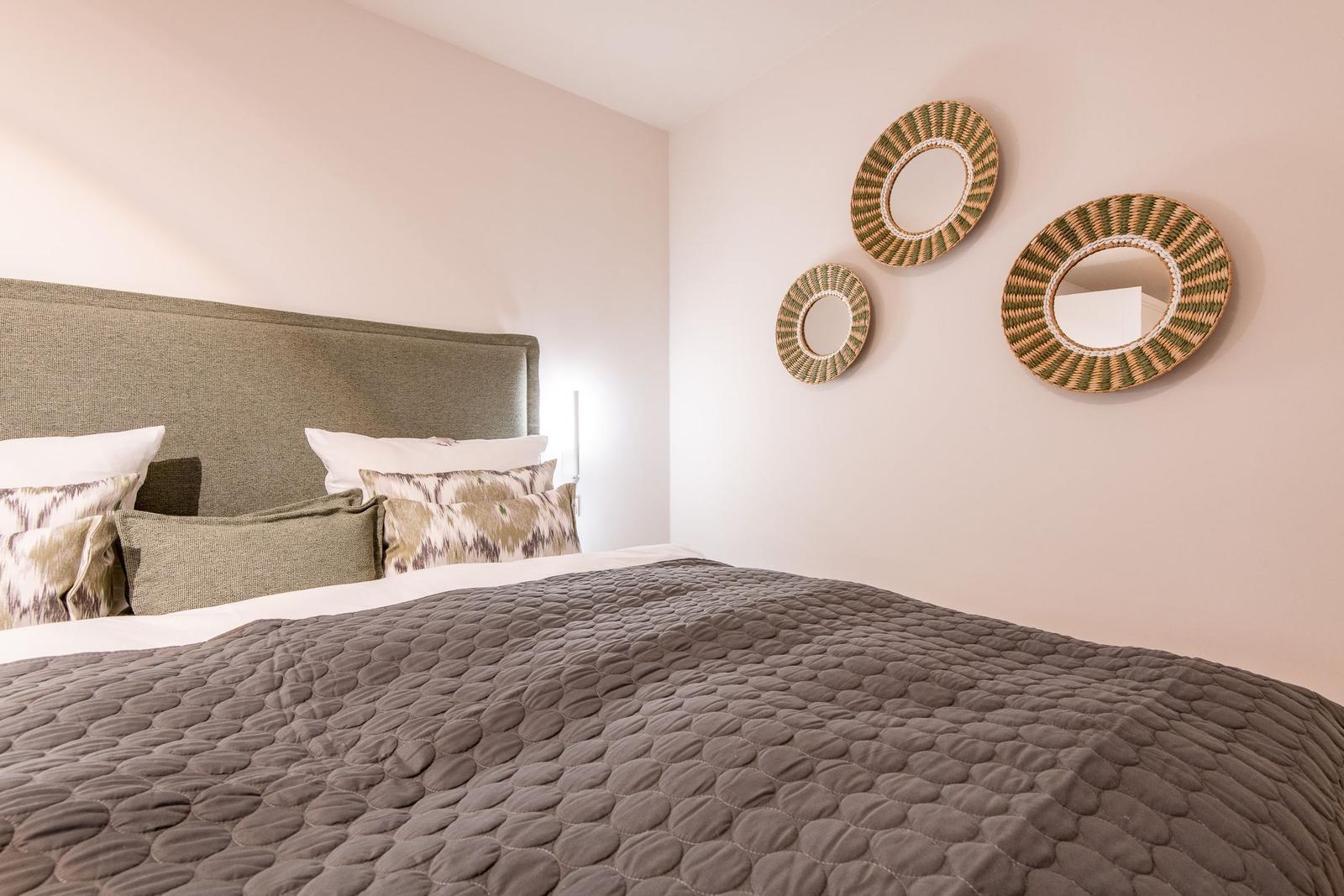 Doppelbett mit Kissen und Wanddekoration aus geflochtenen Runden.