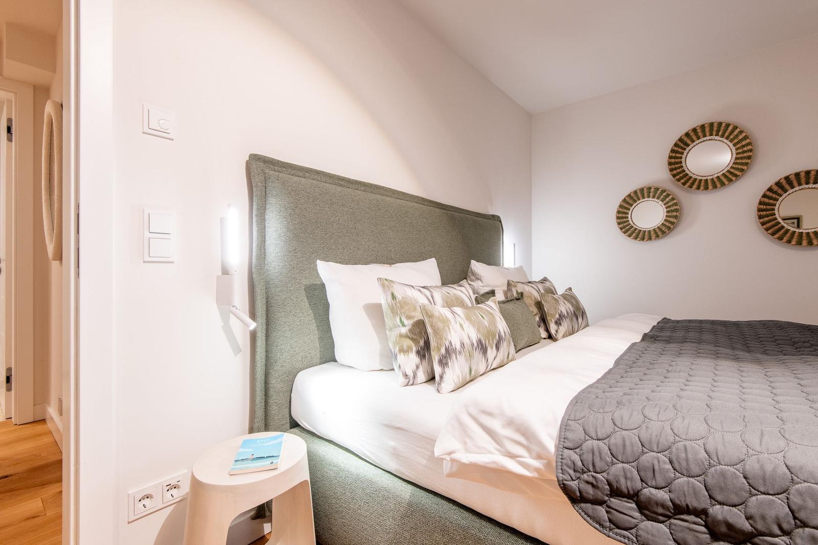 Schlafzimmer mit Bett, Kissen und Wandspiegeln