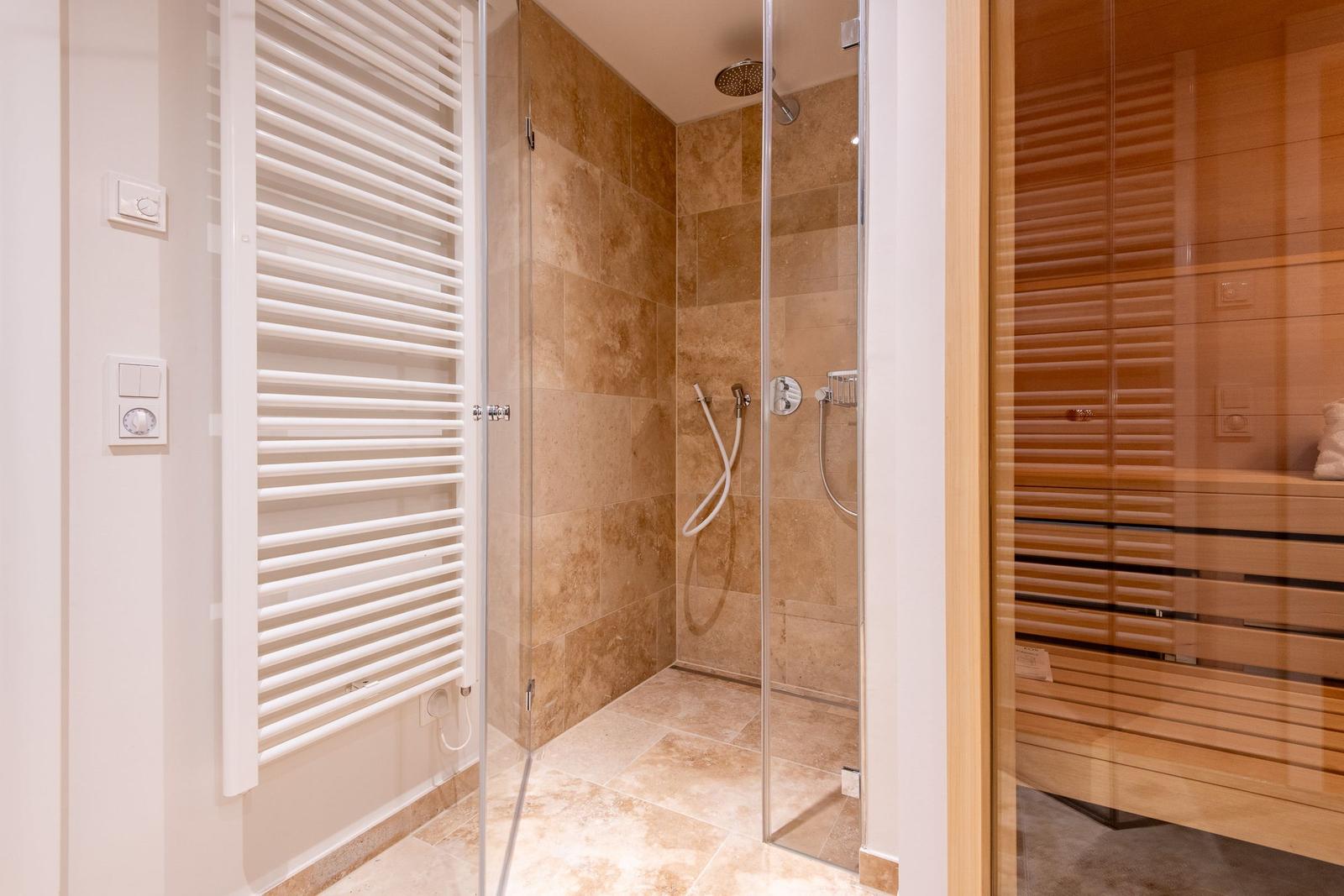 Dusche mit Glaswand, Sauna und Heizkörper an der Wand