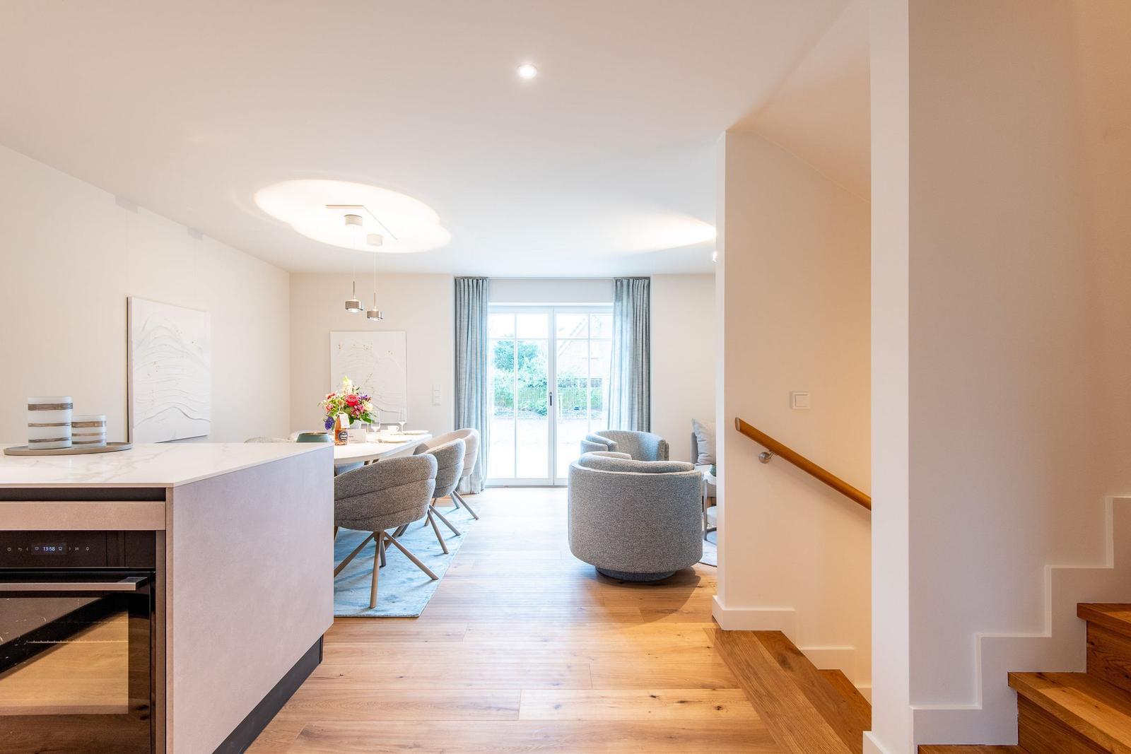 Eingangsbereich mit Treppenhaus, Essbereich und Wohnzimmer mit Sitzgelegenheiten.