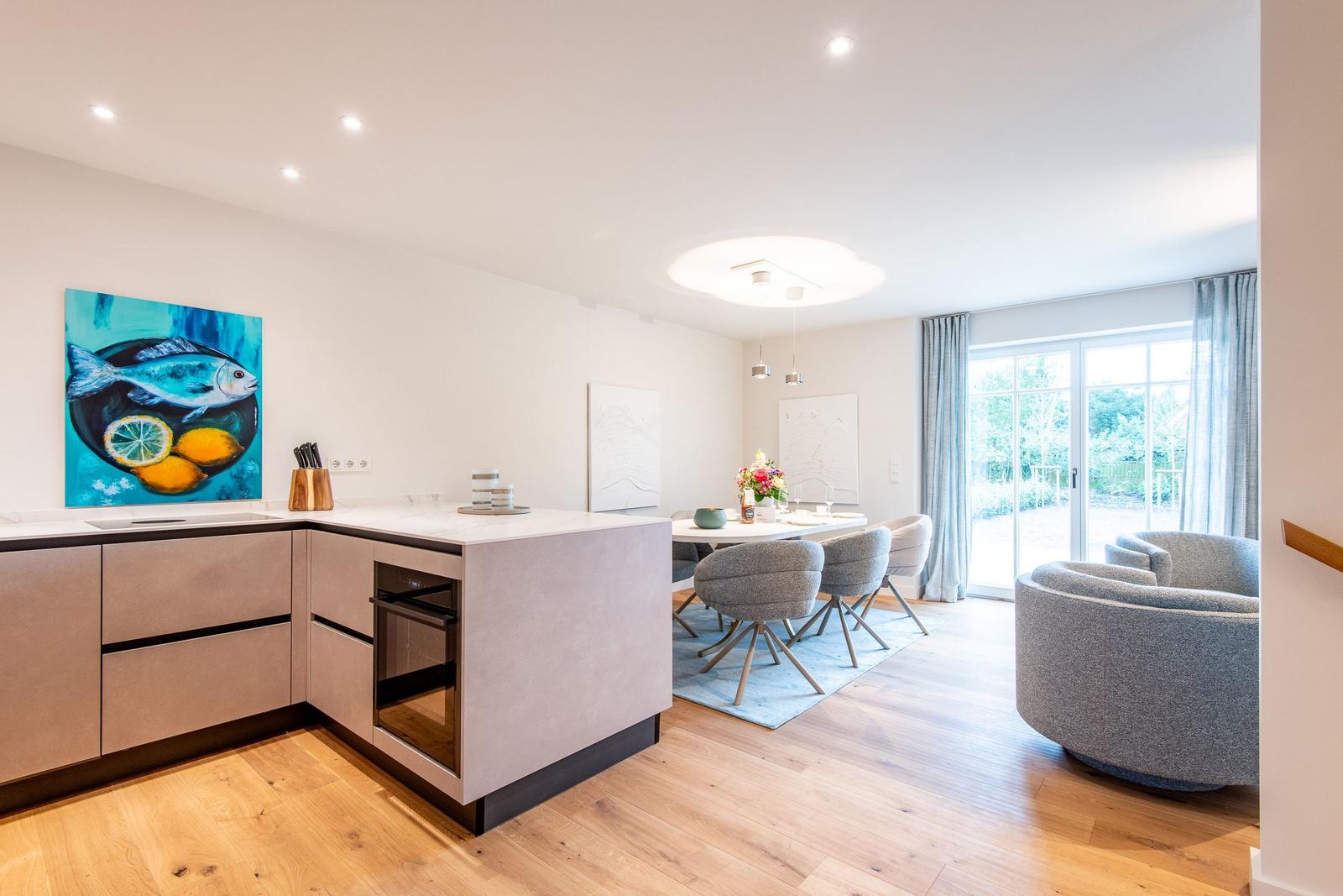 Moderne Küche mit Essbereich und Sitzgelegenheit. Große Fenster mit Blick auf Garten.