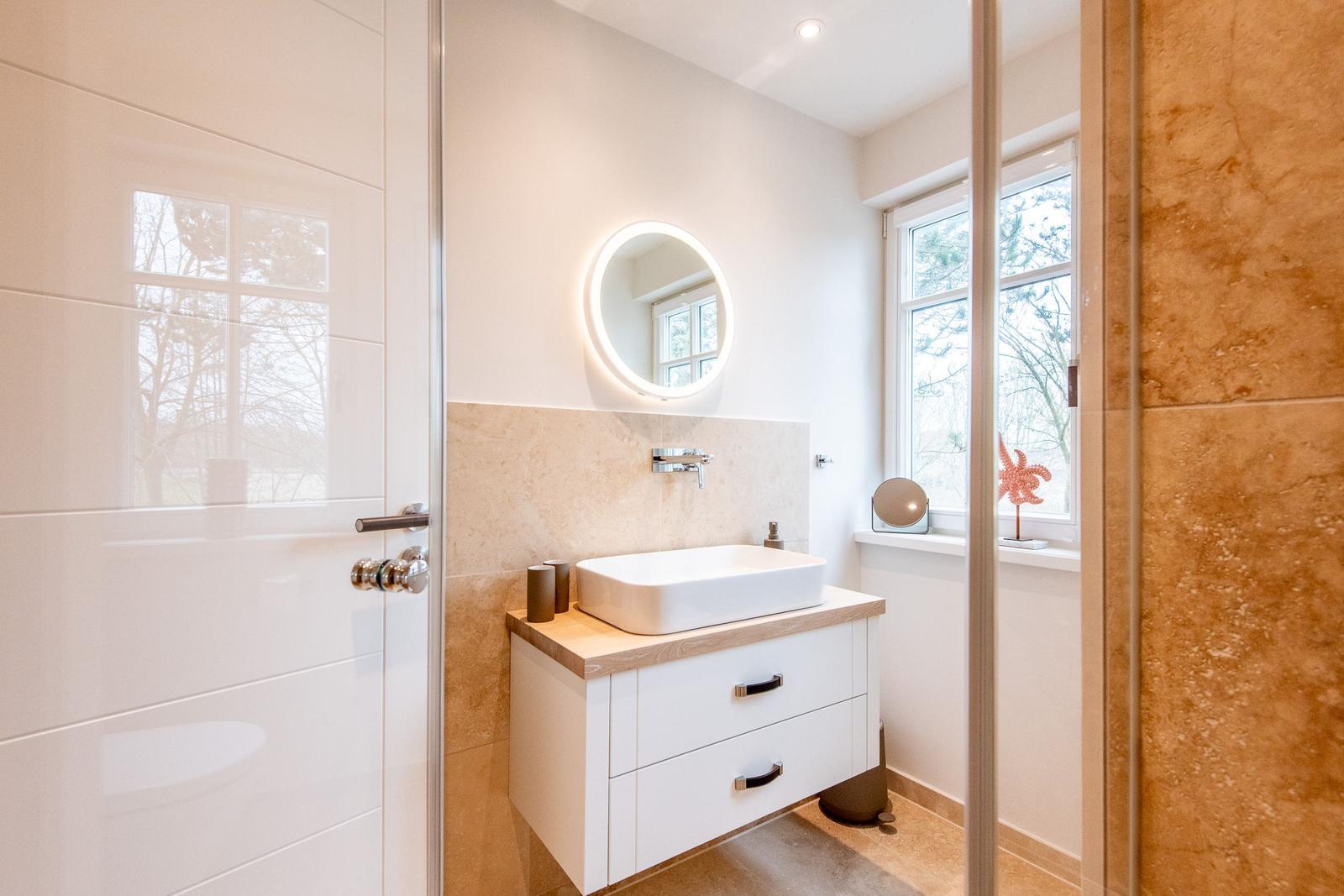 Badezimmer mit Waschbecken, Spiegel und Fenster