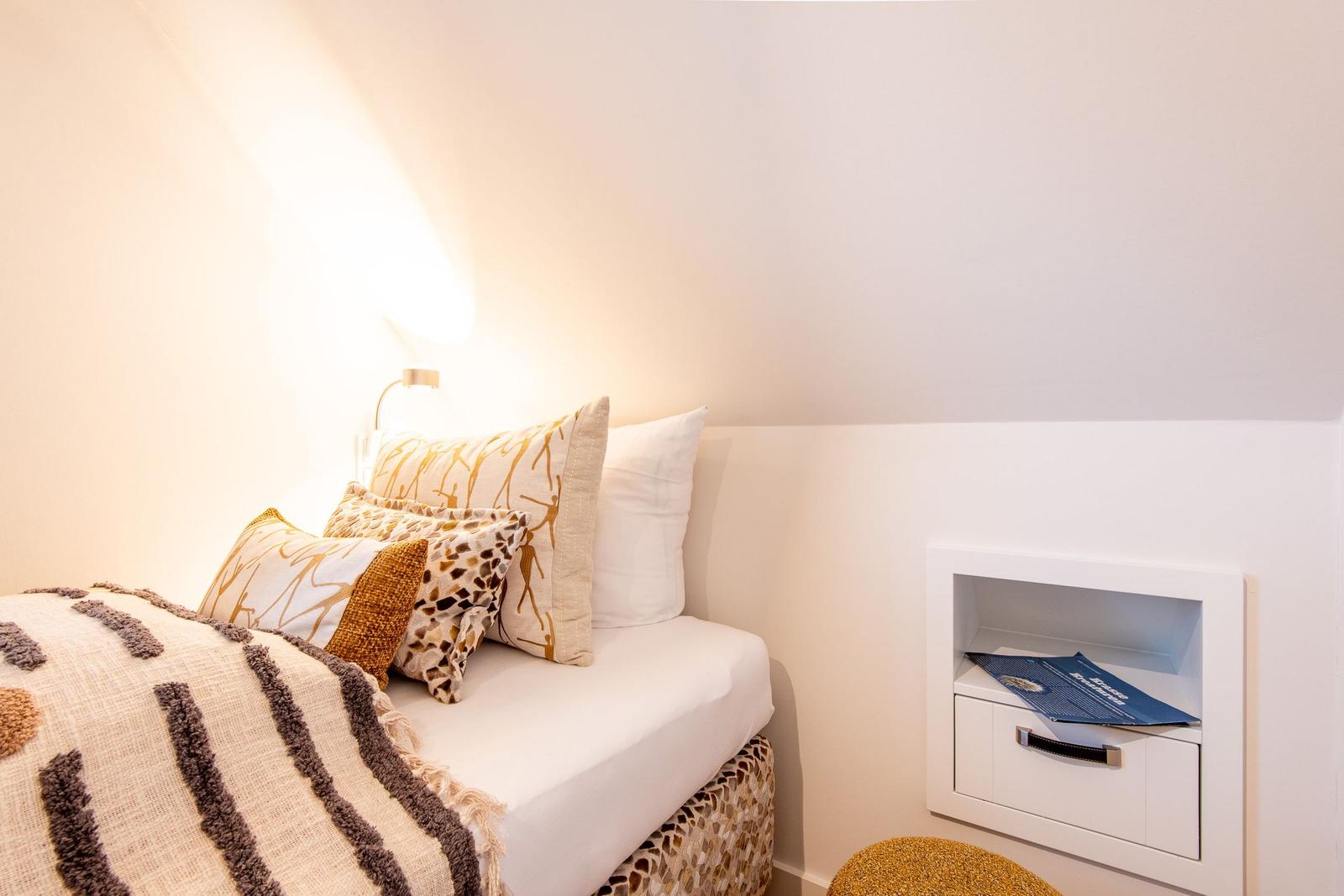 Schlafzimmer mit Bett, Kissen und integriertem Schrank.