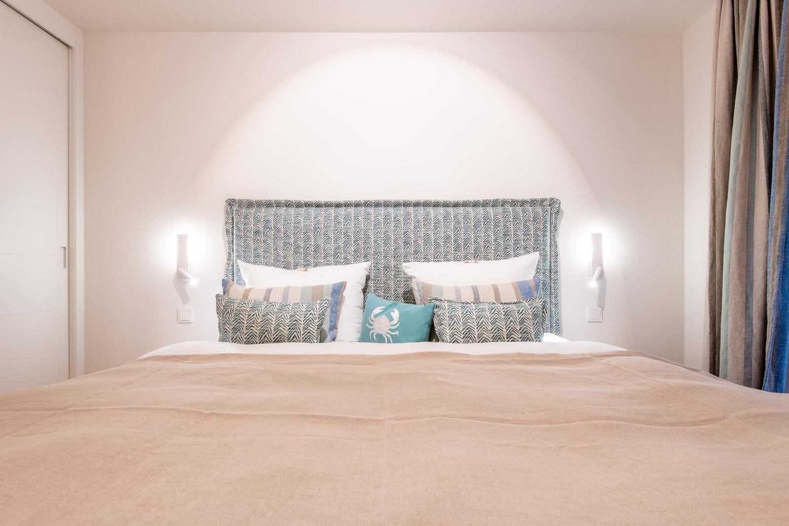 Schlafzimmer mit Bett, Kopfteil und Wandlampen