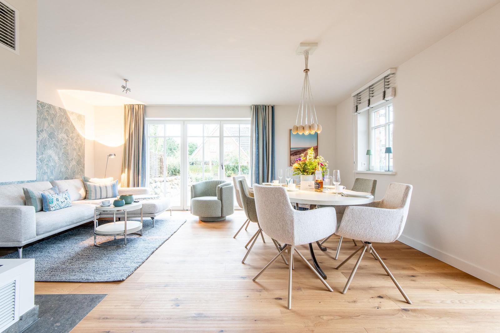 Wohn- und Essbereich mit Sofa, Tisch und Stühlen sowie Fenstern.