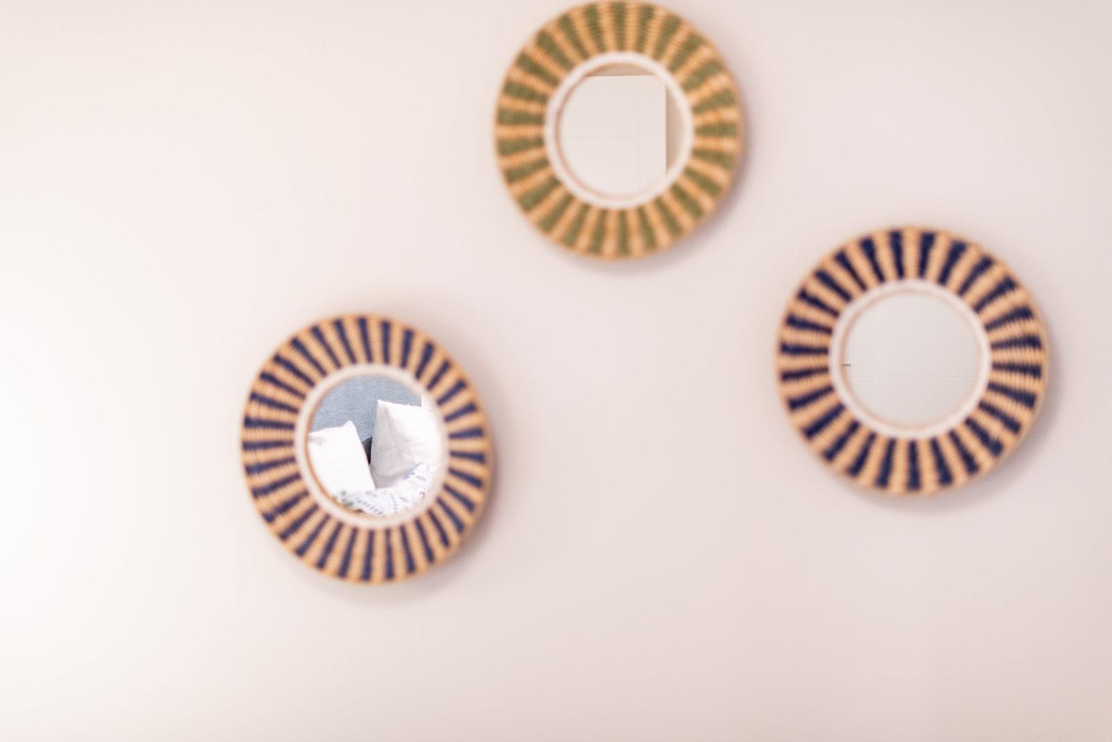 Drei runde Spiegel mit geflochtenen Rahmen an der Wand.