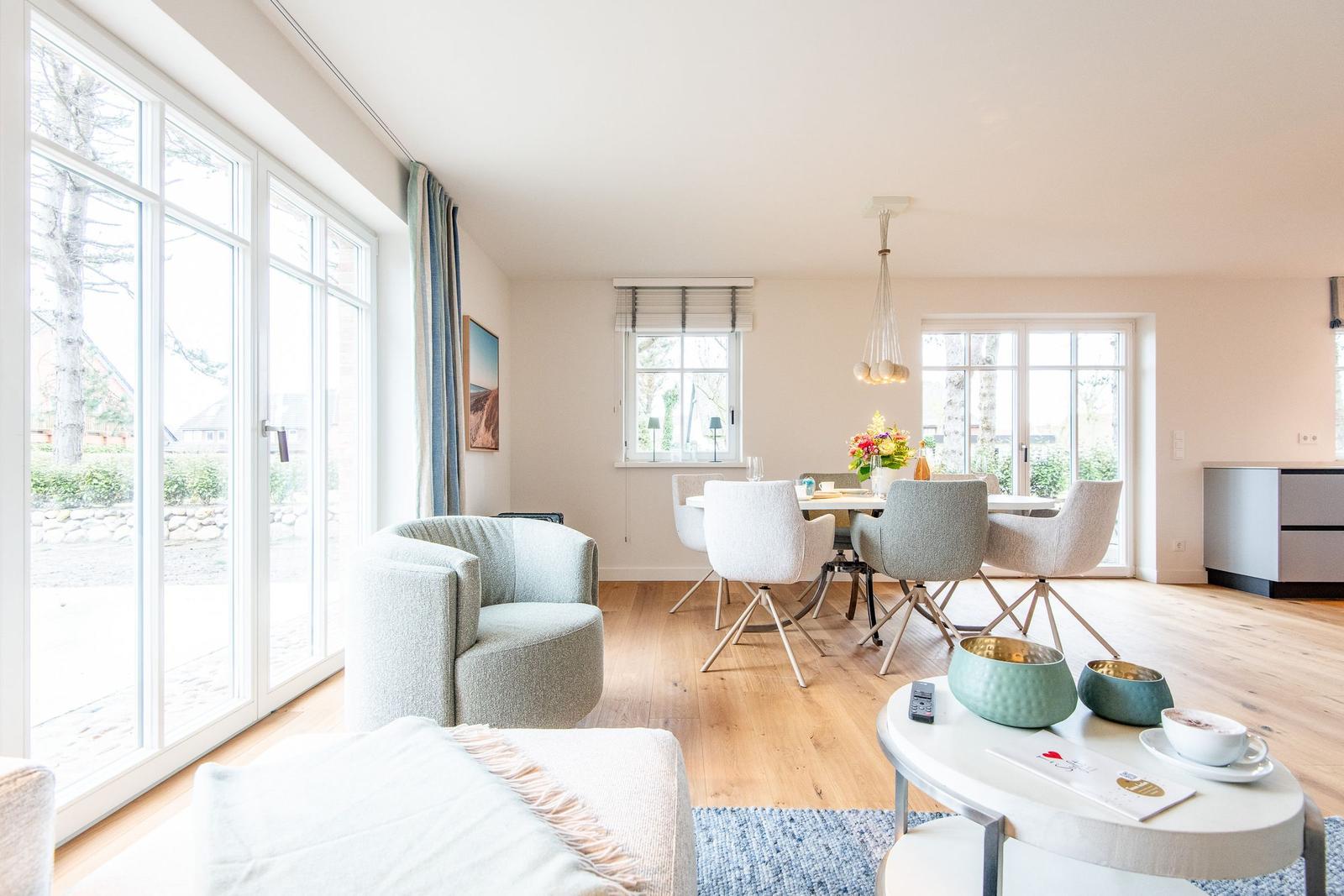 Wohn- und Essbereich mit Holzboden, großen Fenstern und moderner Einrichtung.