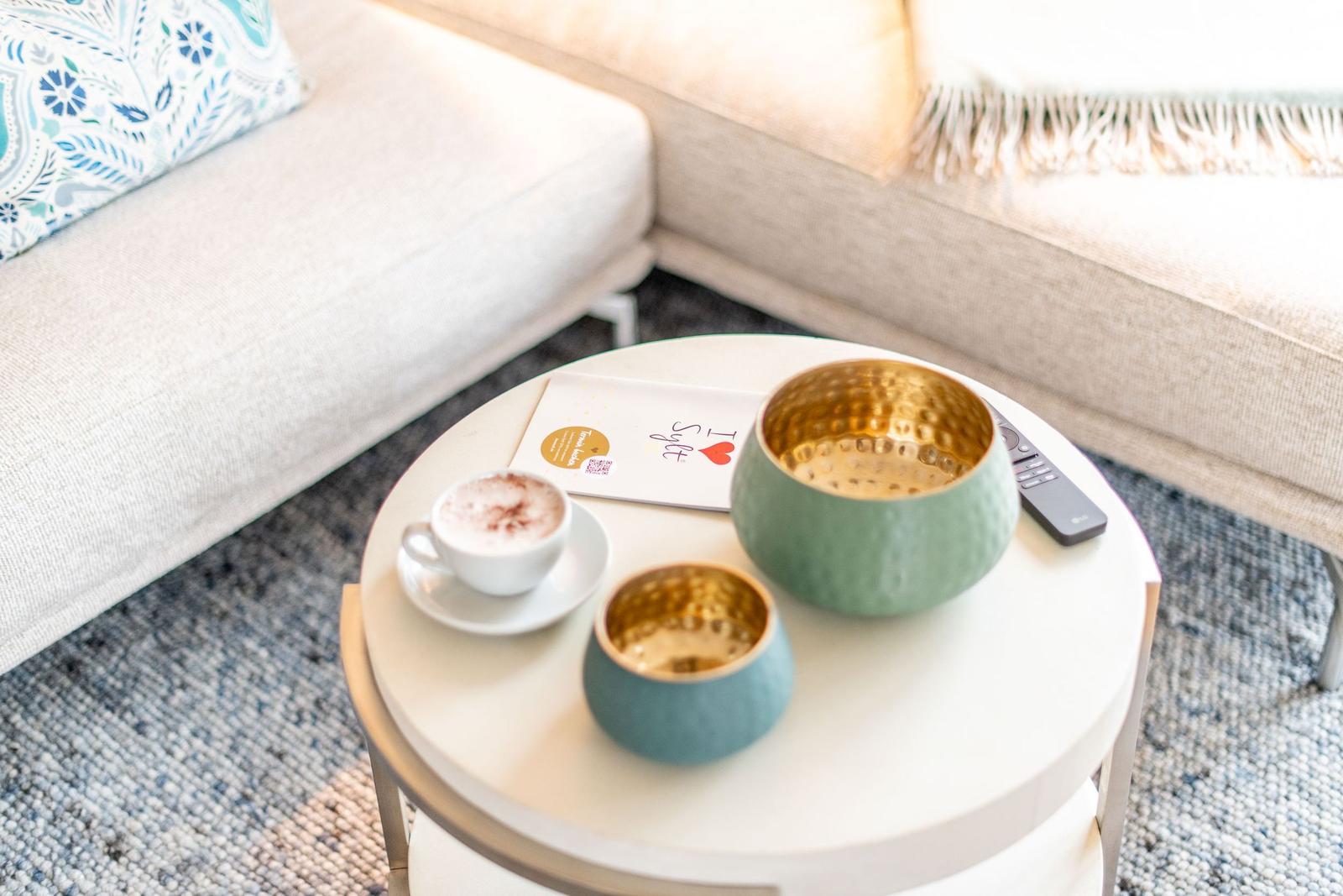 Runde Tisch mit Kaffee, Schale und Fernbedienung vor Sofa