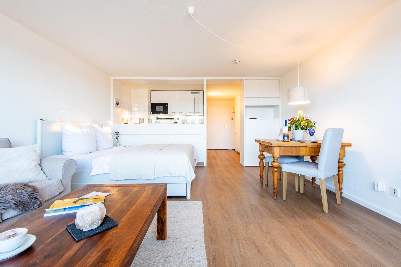 Schlafzimmer mit Bett, Sofa, Esstisch und Küchenbereich.