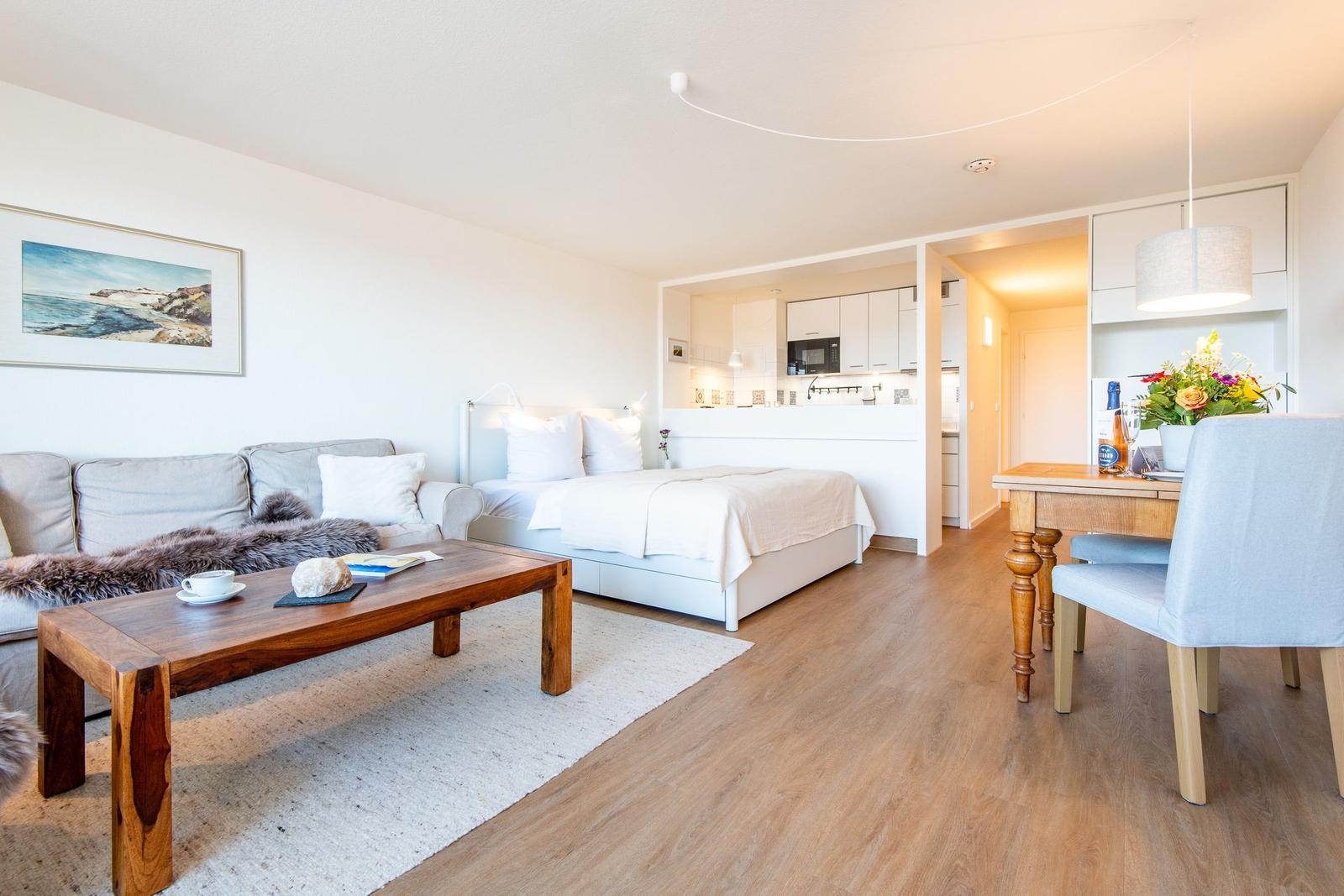 Wohnbereich mit Sofa, Bett, Esstisch und Küchenbereich.