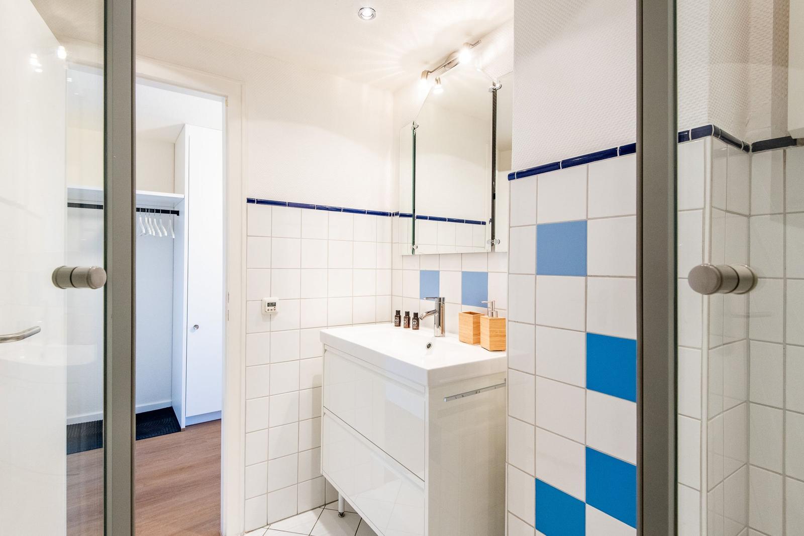 Badezimmer mit Dusche, Waschbecken und blau-weißen Fliesen