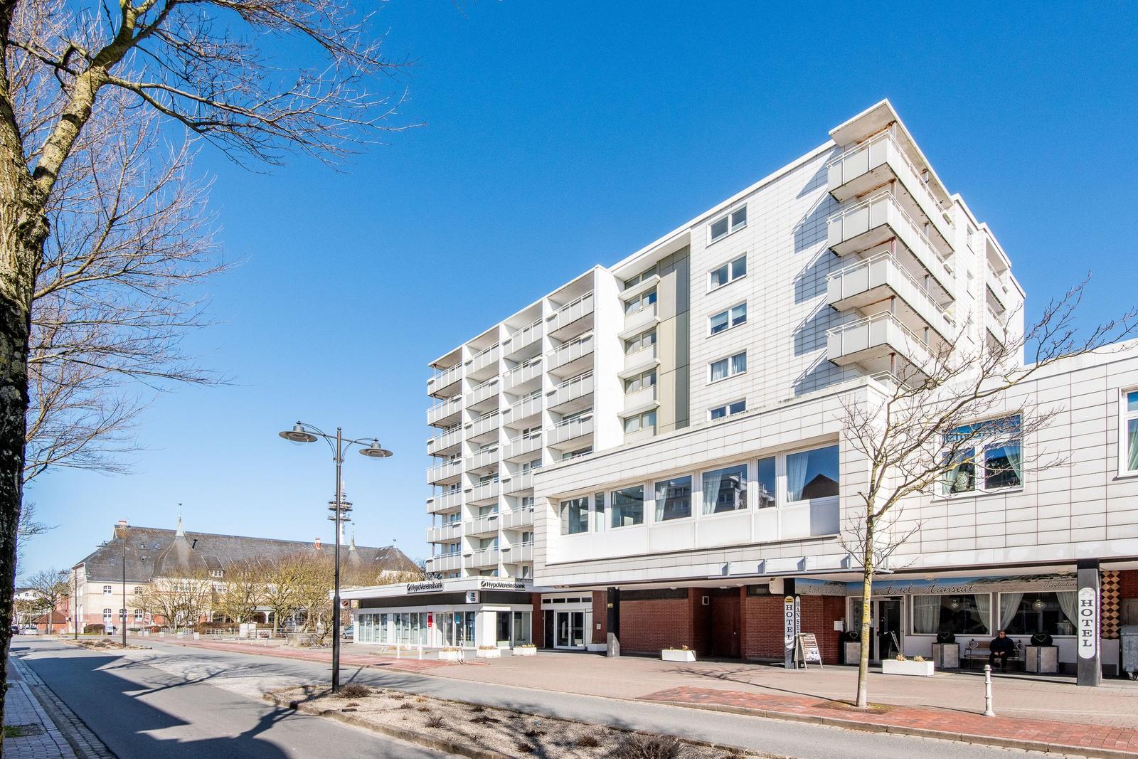 Hotelgebäude mit Balkonen und Eingangsbereich an sonnigem Tag.