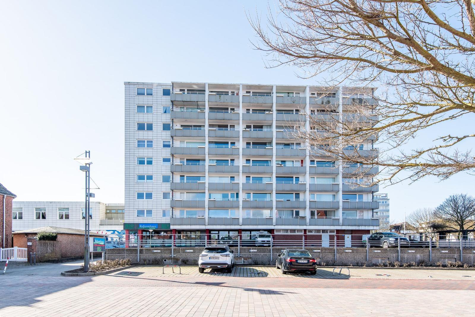 Hochhaus mit Balkonen und Parkplatz vorne