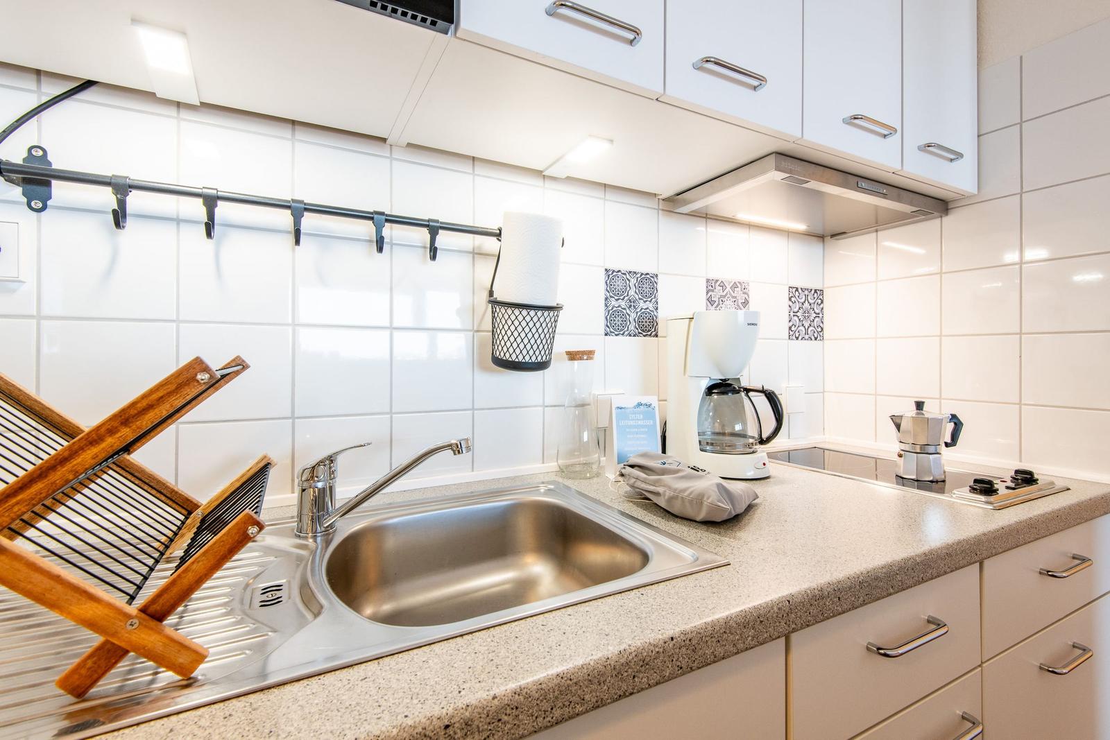 Küche mit Spüle, Kochfeld und Küchengeräten.