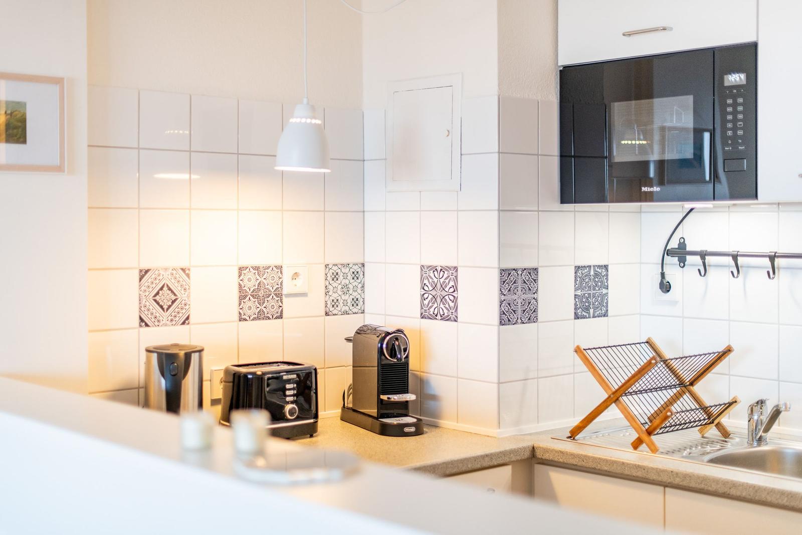 Küche mit Mikrowelle, Toaster und Kaffeemaschine an der Arbeitsfläche.