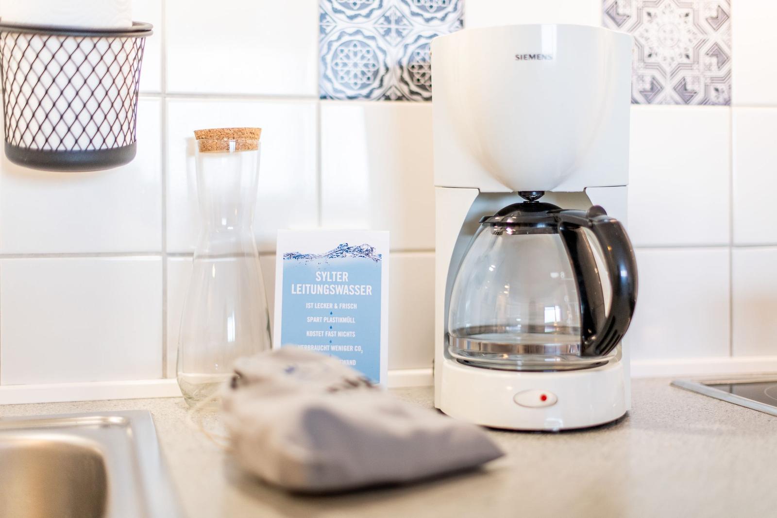 Küchenzeile mit Kaffeemaschine, Wasserglas und Informationskarte.