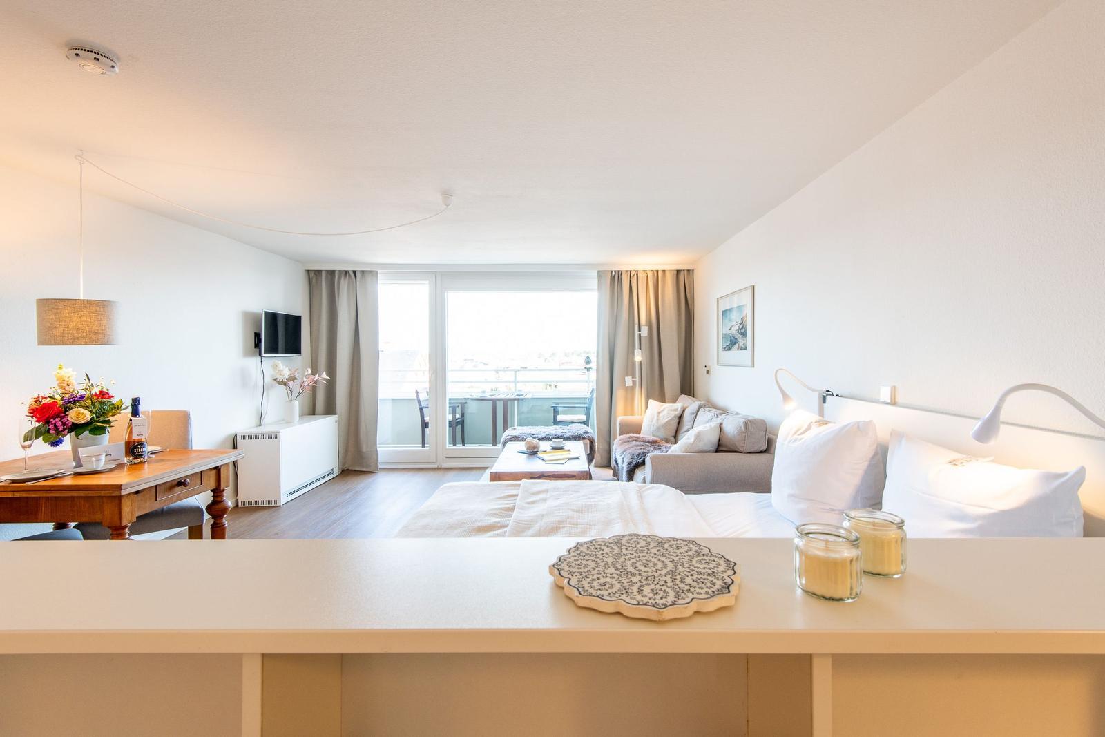 Ein Schlafzimmer mit Blick auf Balkon, Sofa und Esstisch.