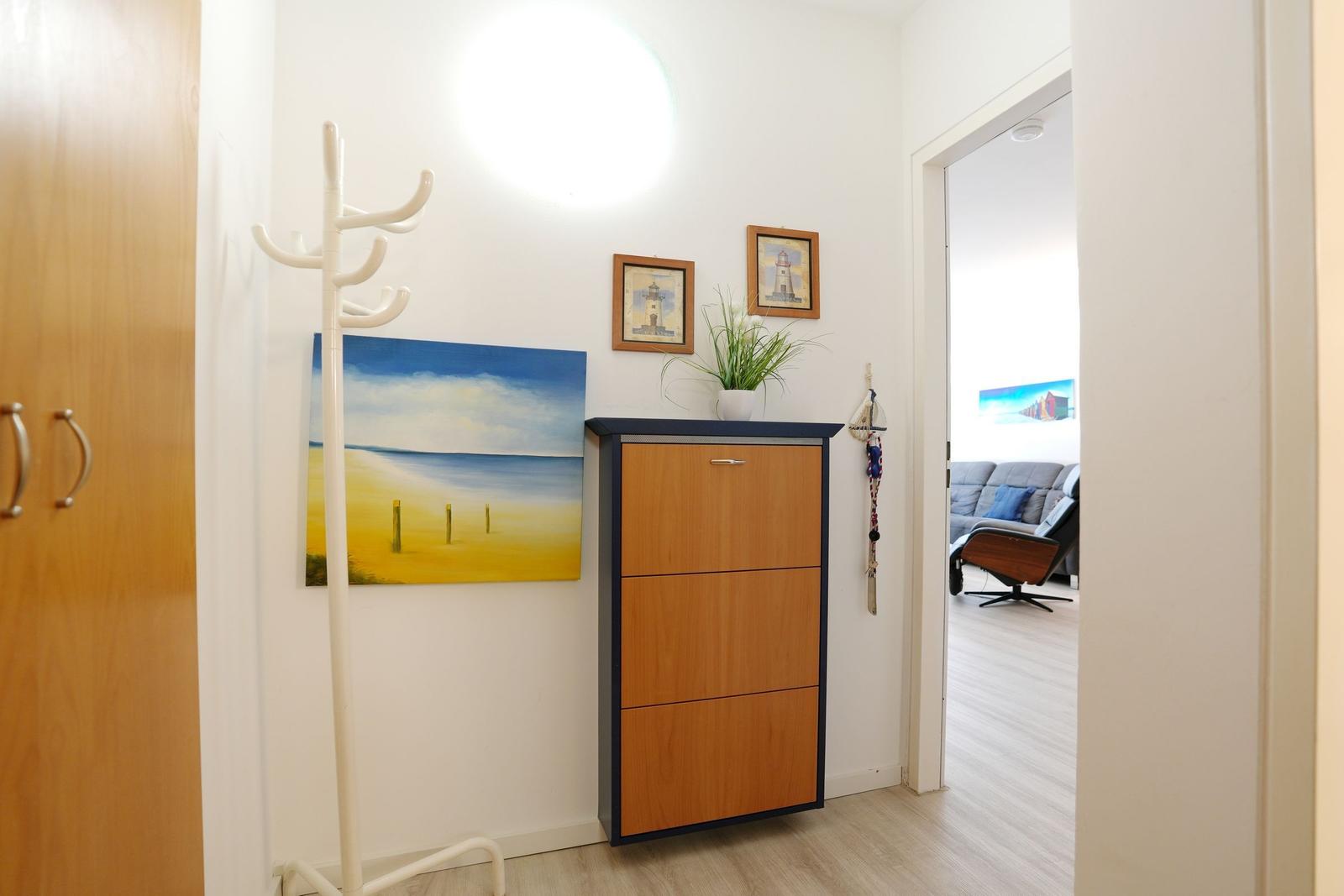 Entryway with coat rack, cabinet, and wall art. View into living room.