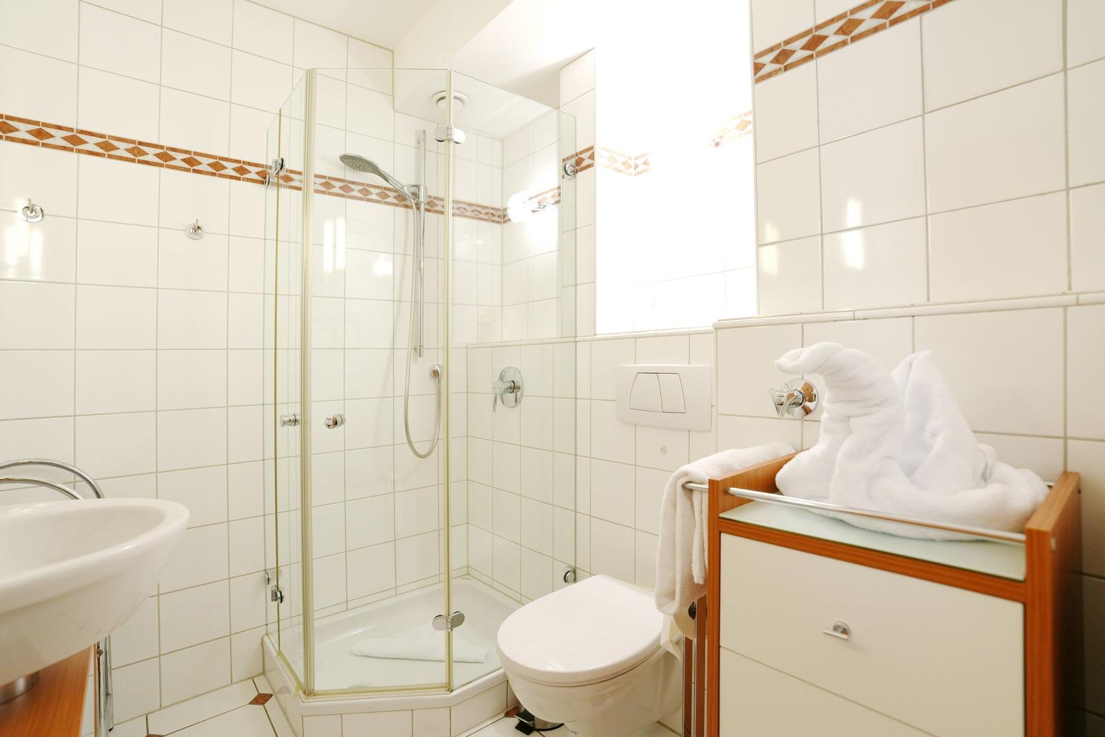 Bathroom with shower, toilet, and sink. Towel shaped like a duck.