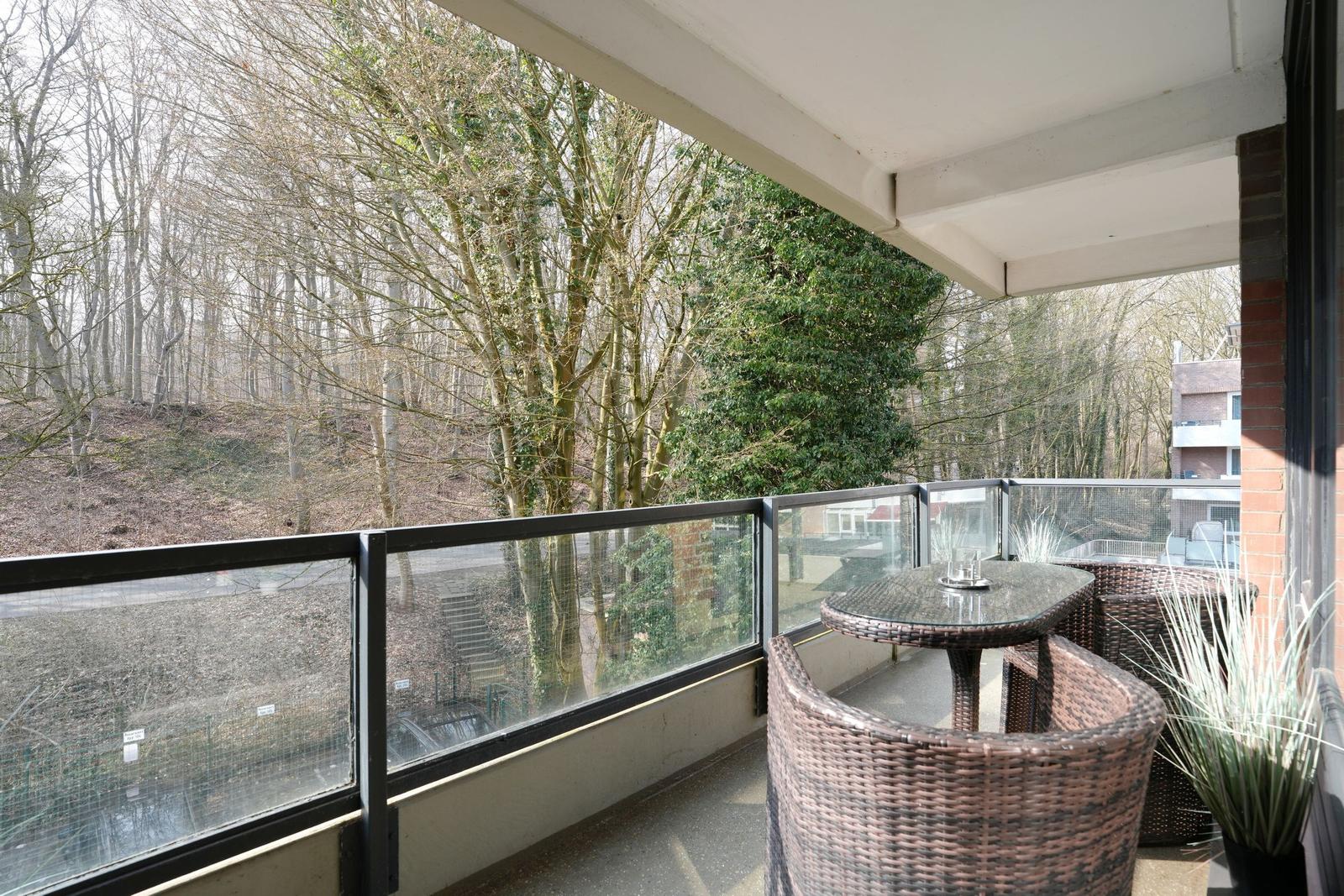 Balcony with seating area and view into a forest.