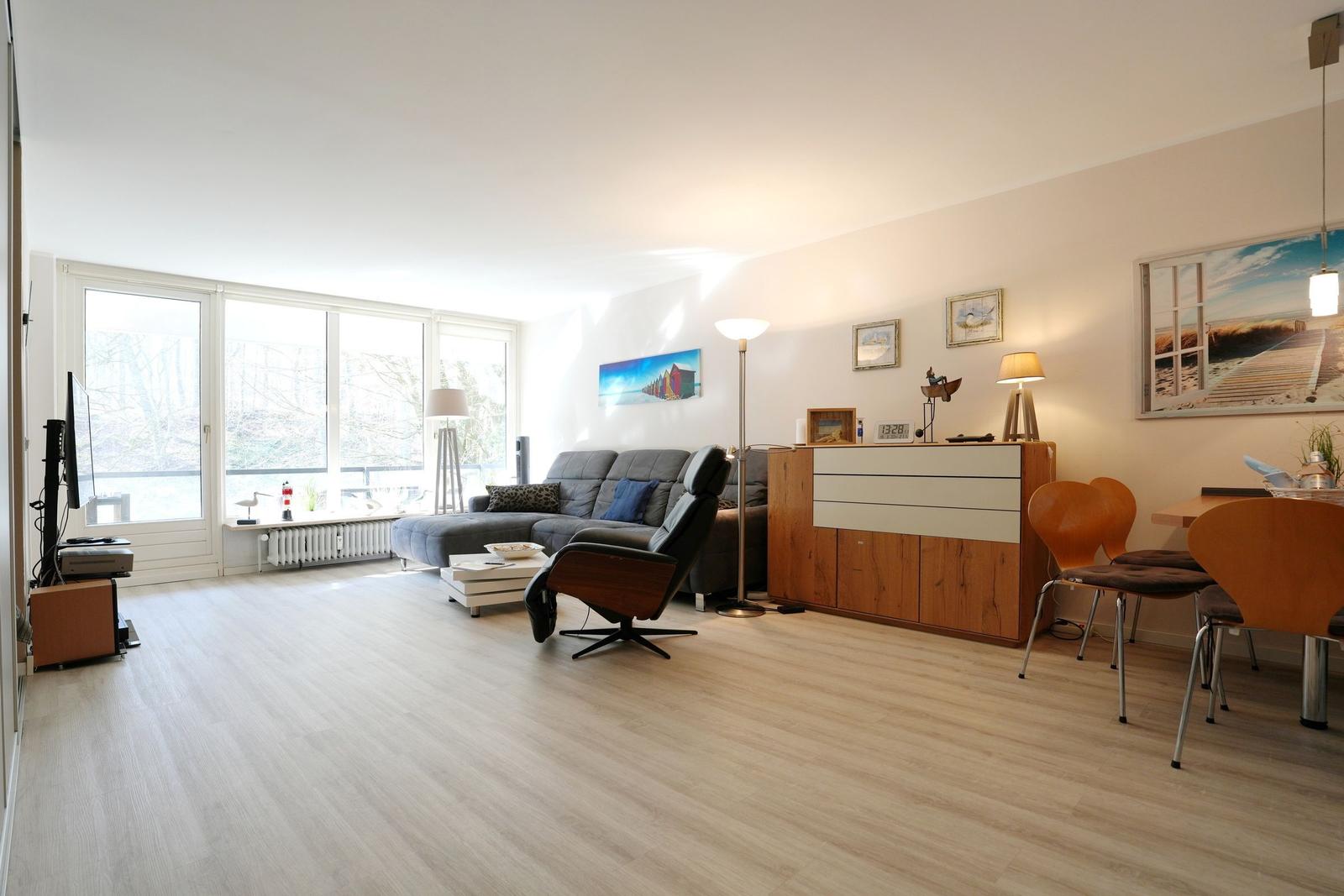 Living room with sofa, chair, dining table and large windows.