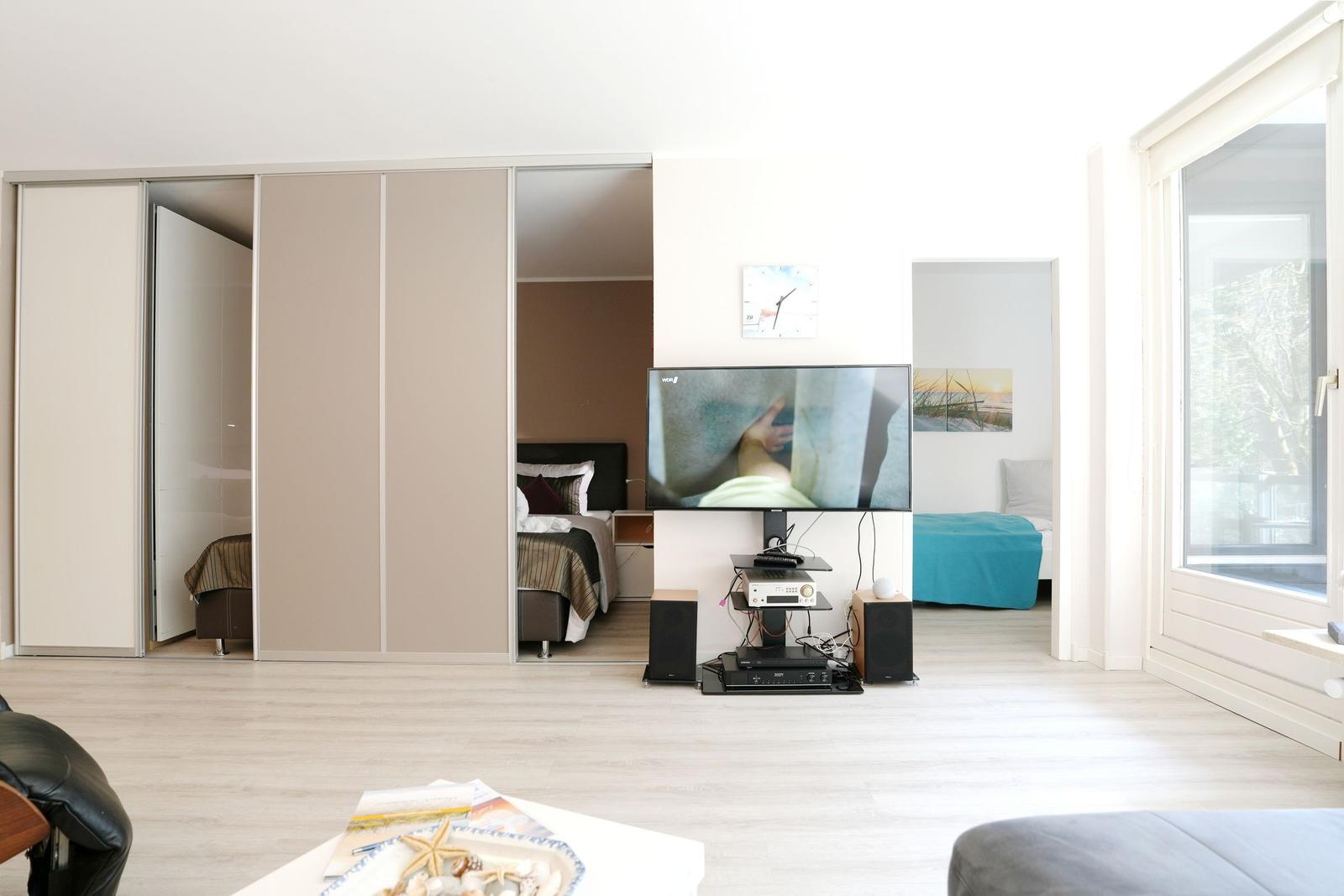 Living area with TV, bedrooms, and window. Furniture and fixtures visible.