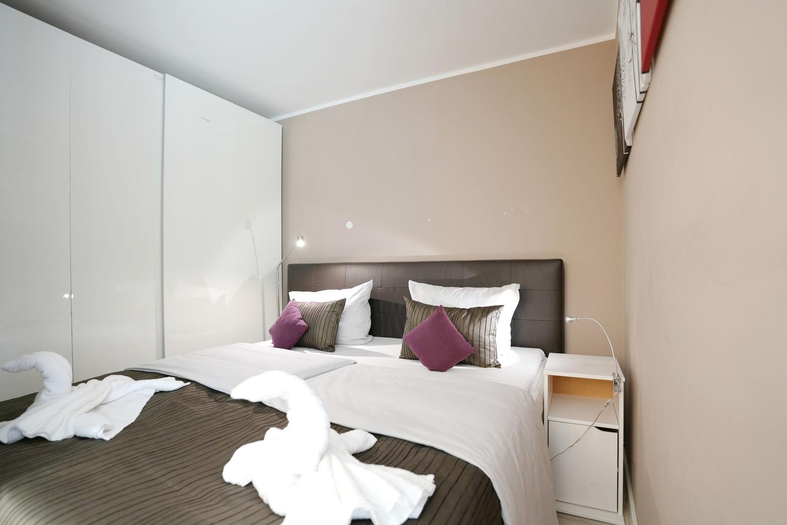 Bedroom with double bed, white bedside tables, and large wardrobe.