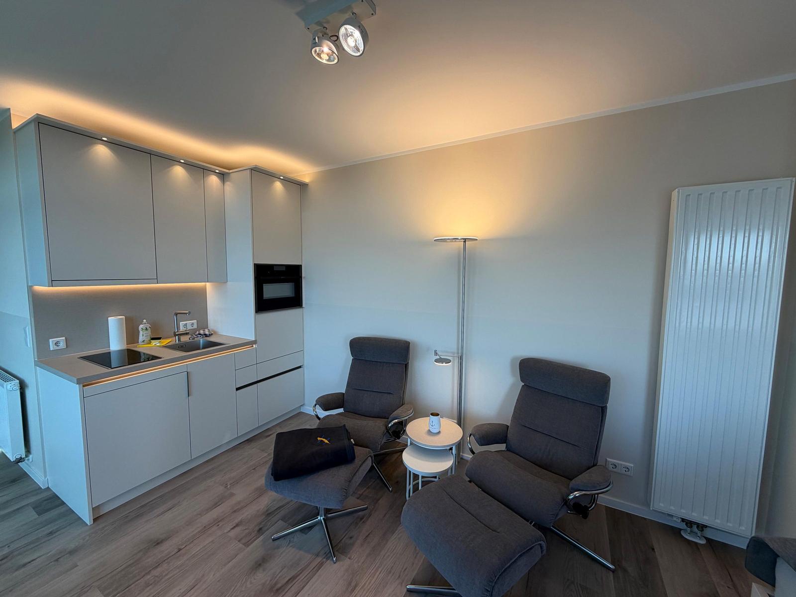 Küche mit zwei Sesseln und Fußstützen. Moderne Einbauküche mit Licht.