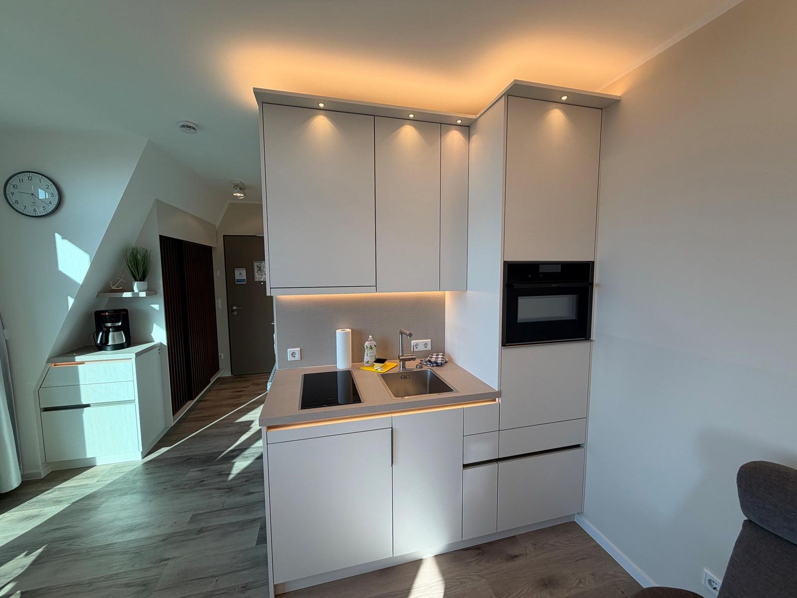 Moderne Küche mit integriertem Ofen und Edelstahl-Spüle.