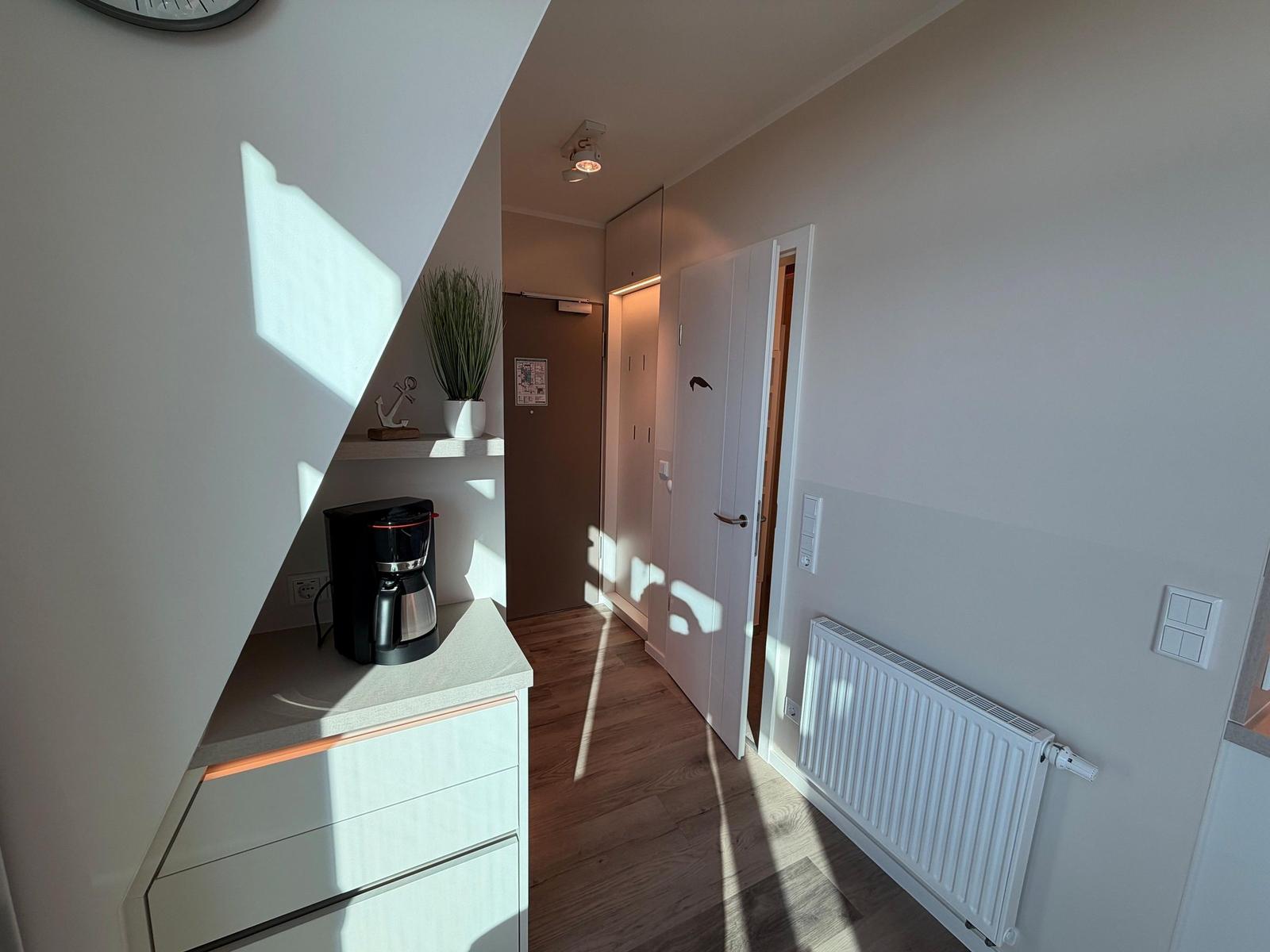 Eingangsbereich mit Kaffeemaschine, Pflanze und Heizung.