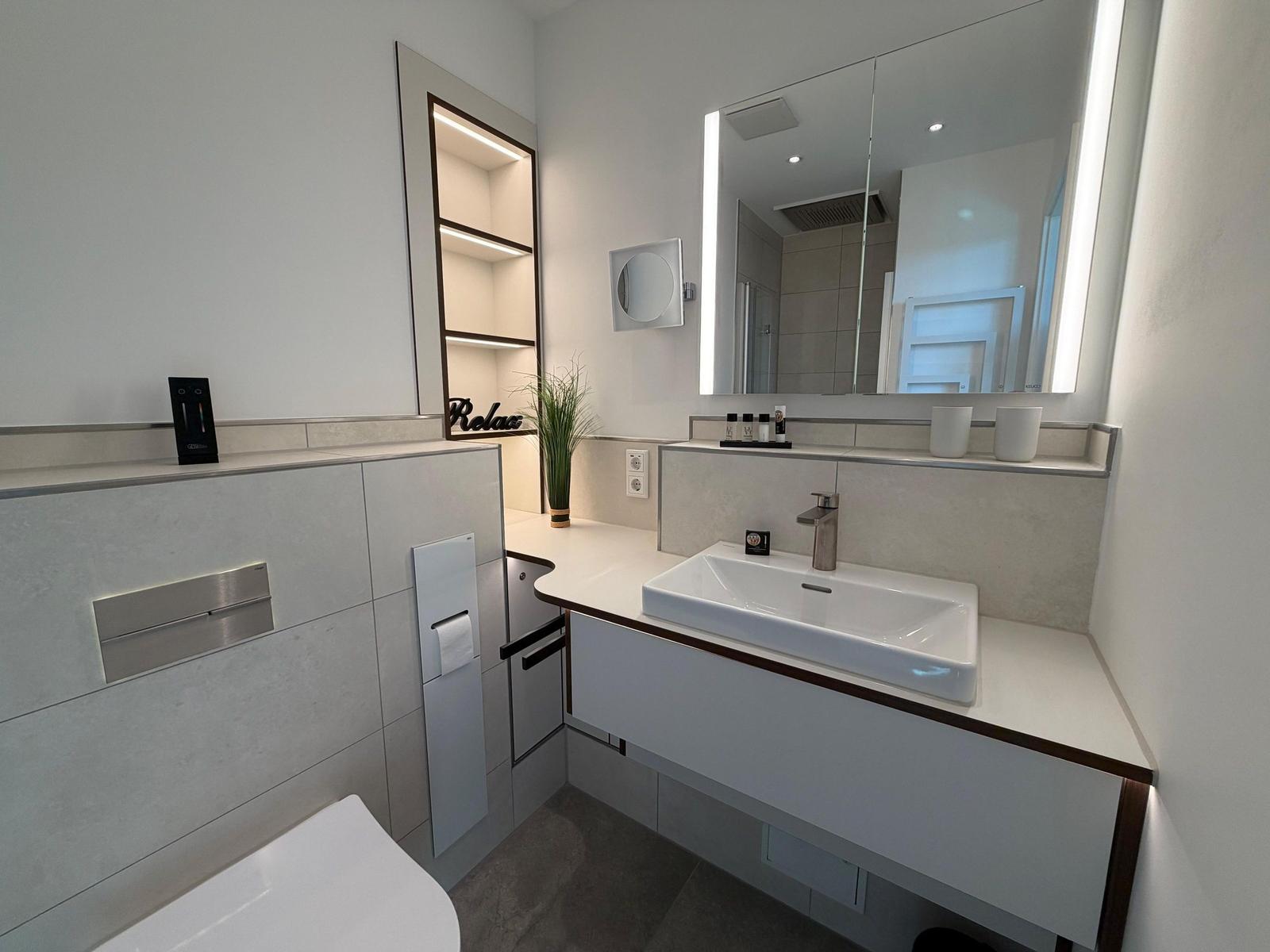 Moderne Badezimmer mit Waschtisch, Spiegel und Toilette.