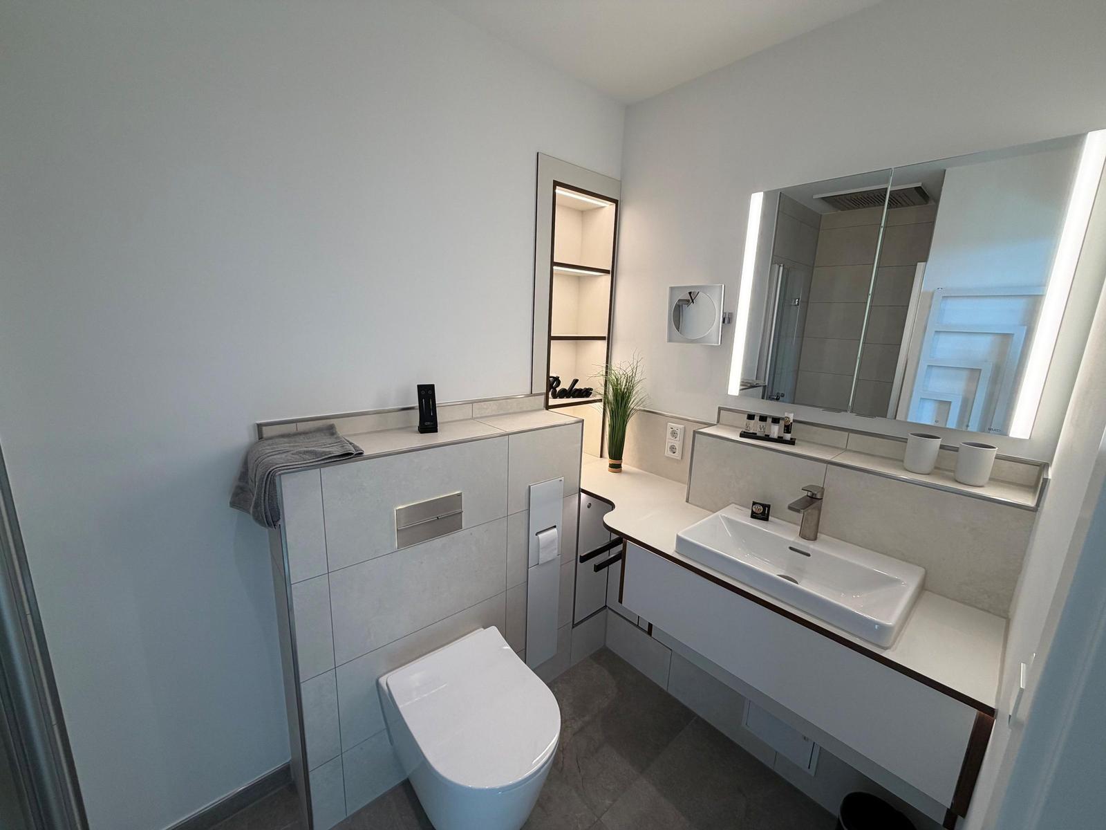 Badezimmer mit Waschbecken, Spiegel und Toilette