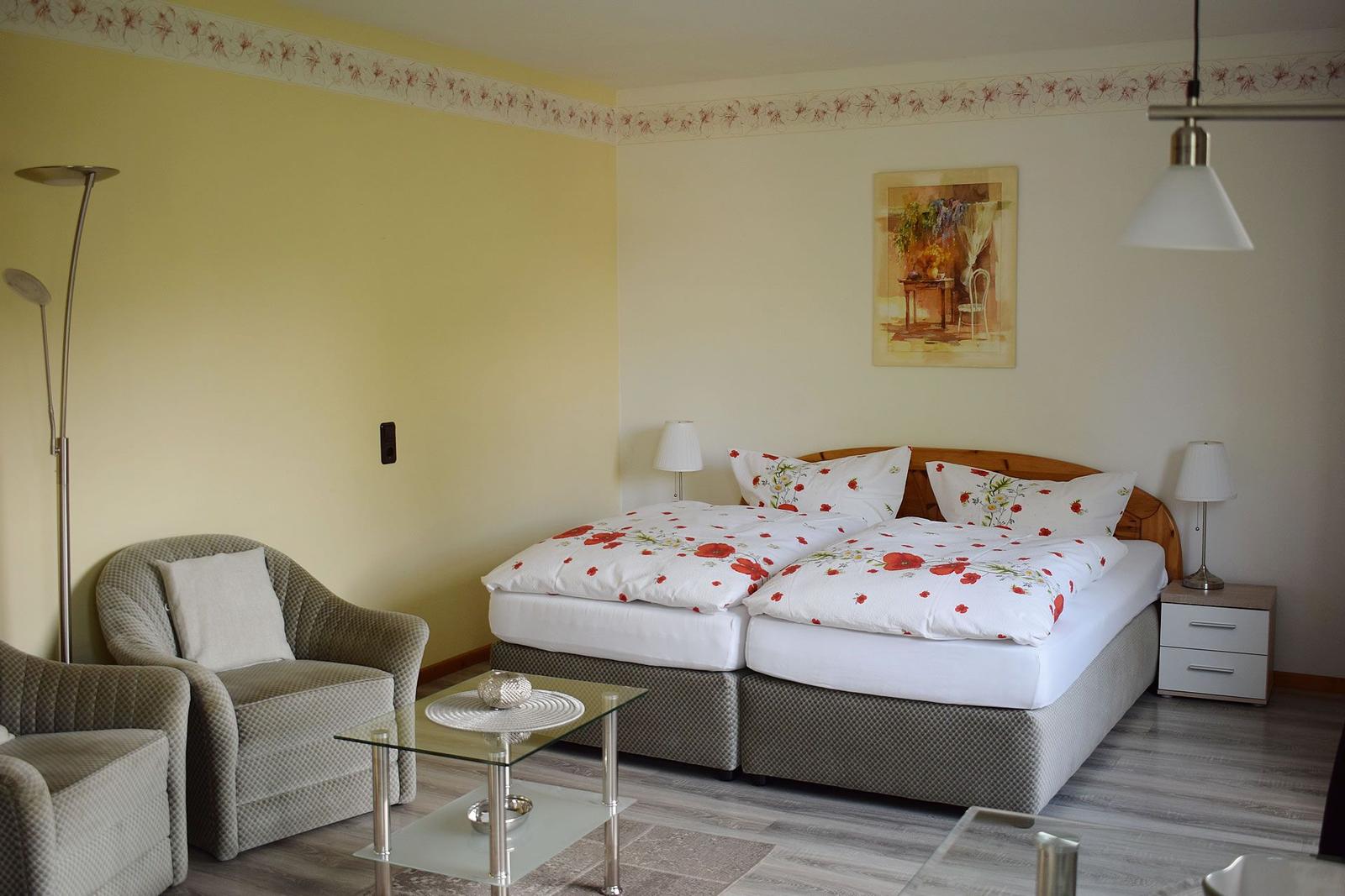 Zimmer mit Doppelbett, Sessel und Glas-Tisch