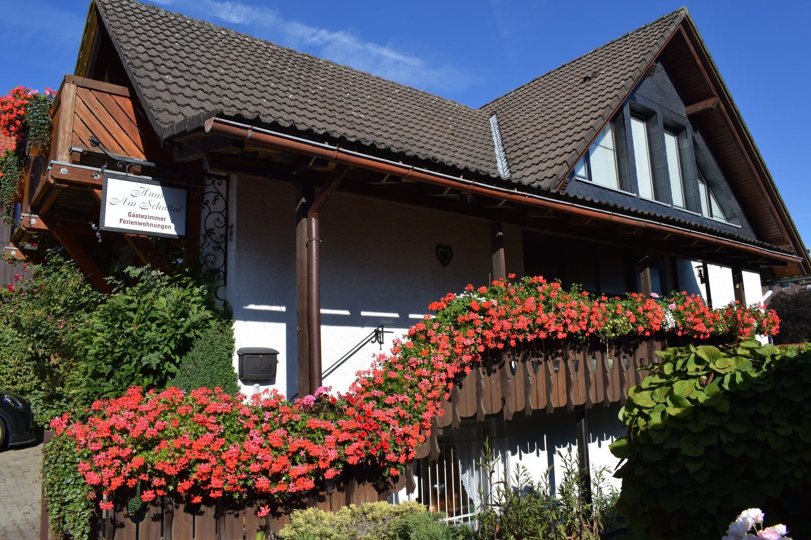 Haus mit Blumen und Schild für Gästezimmer und Ferienwohnungen.