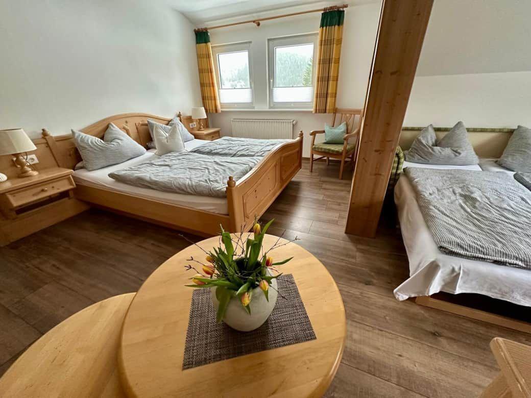 Zwei Schlafzimmer mit Holzbetten und Fenstern mit Vorhängen.