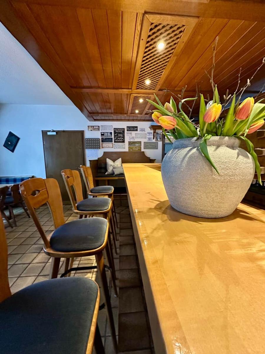 Holzbar mit Stühlen und Blumenarrangement im Raum