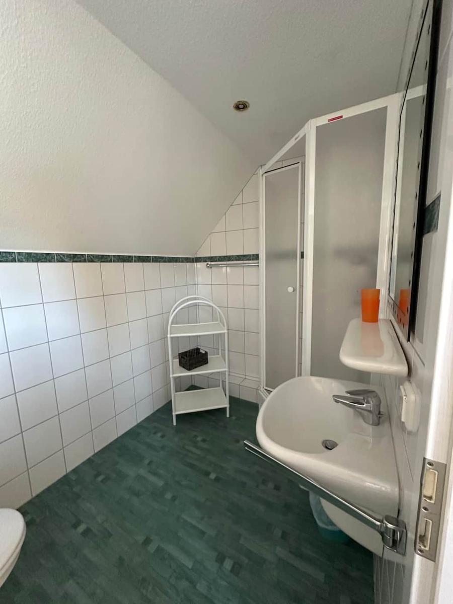 Badezimmer mit Dusche, Waschbecken und Toilette unter schrägem Dach