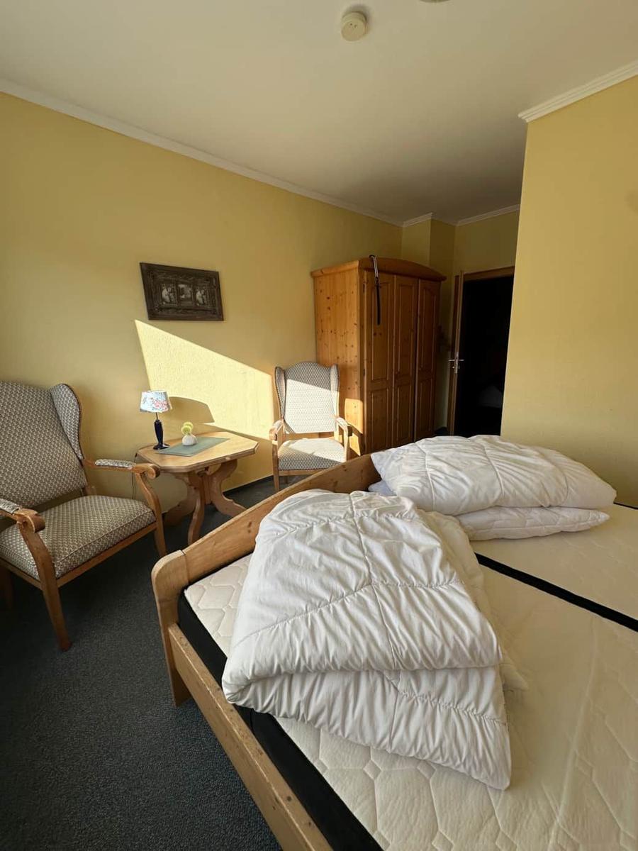 Ein Schlafzimmer mit Bett, zwei Stühlen, Tisch und Kleiderschrank.