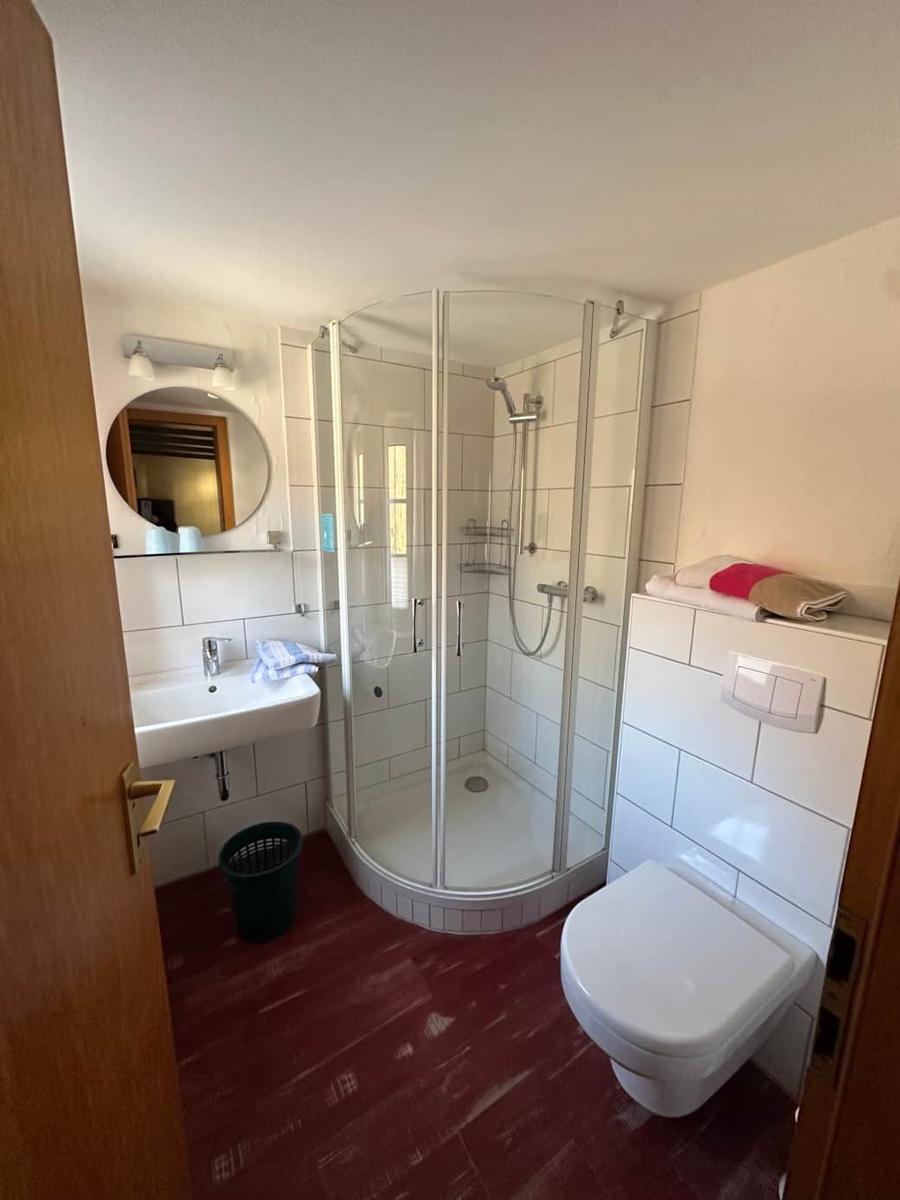 Badezimmer mit Dusche, Waschbecken und Toilette.