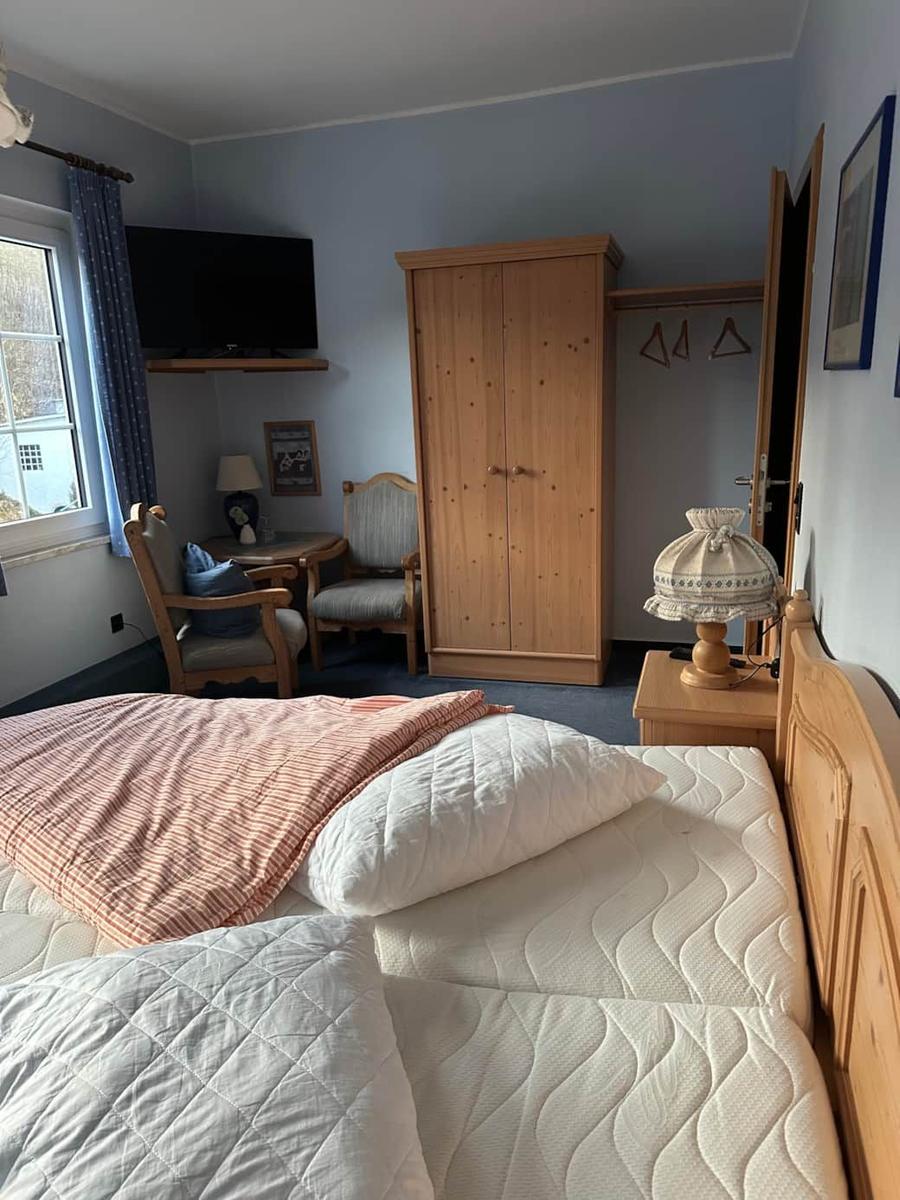 Schlafzimmer mit Bett, Kleiderschrank und Fernseher an der Wand.