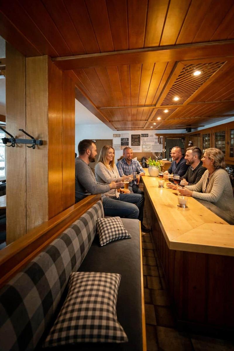 Gruppe sitzt an Holzbar mit Sitzbank und Kissen.